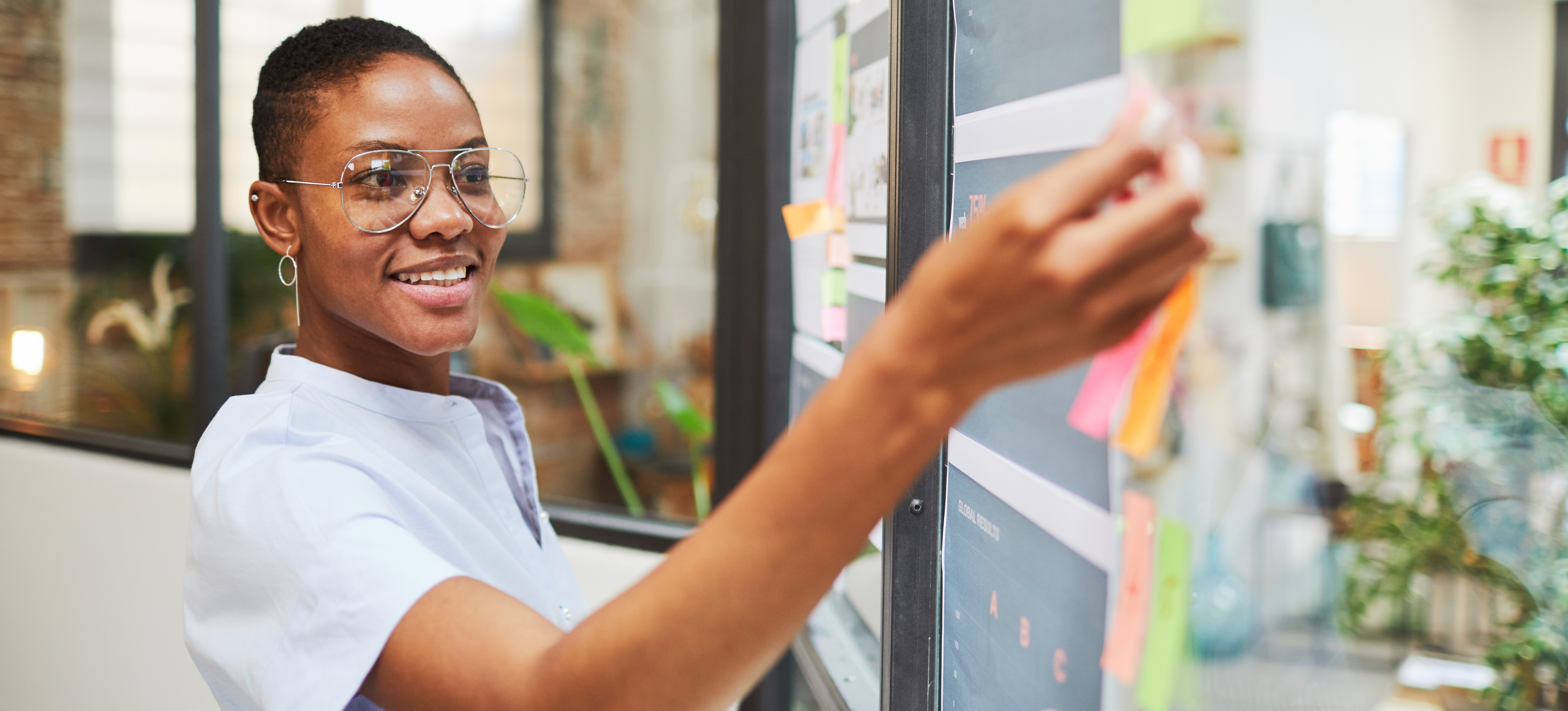 [Featured image] A UX designer maps out a user story with sticky notes on a window.
