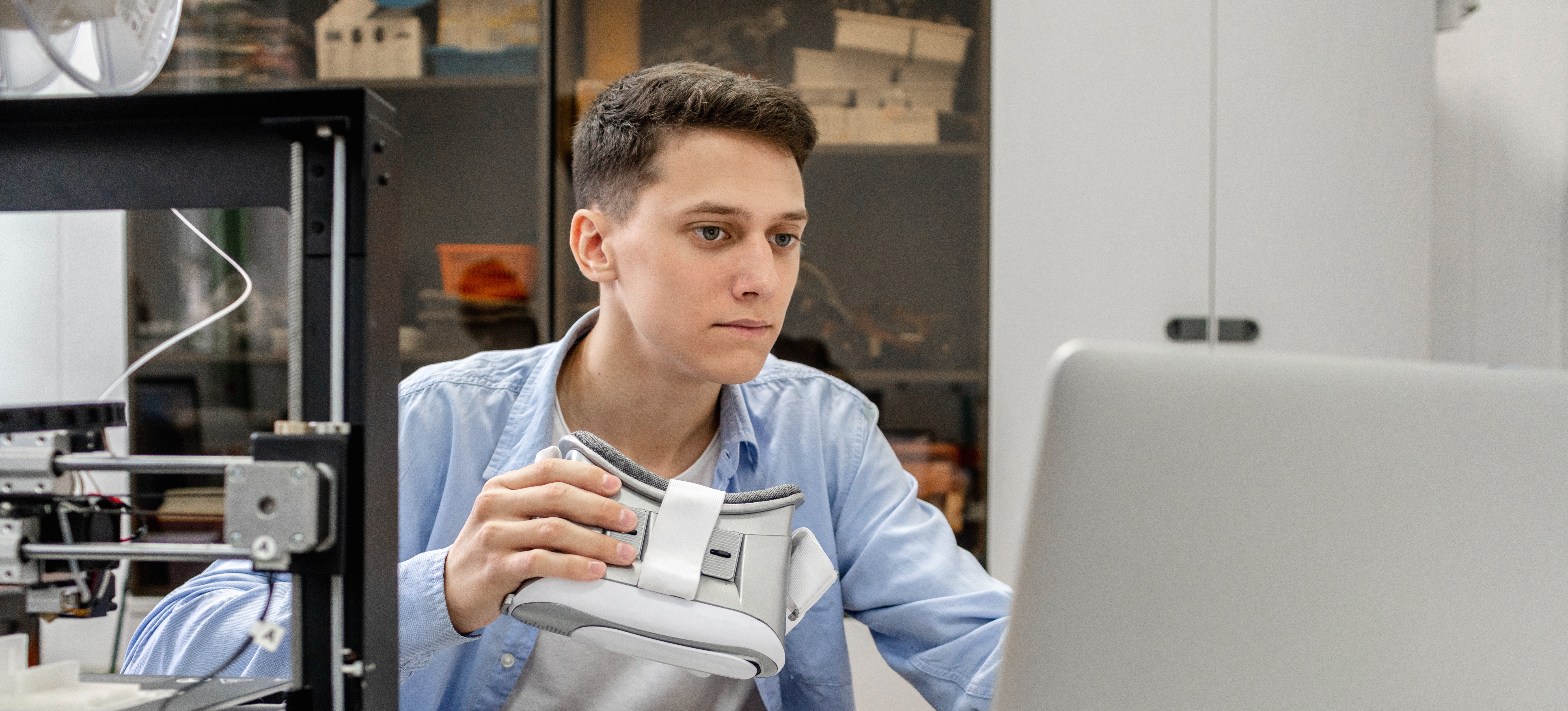 [Featured image] A data science major in a blue shirt and holding goggles works on a computer.