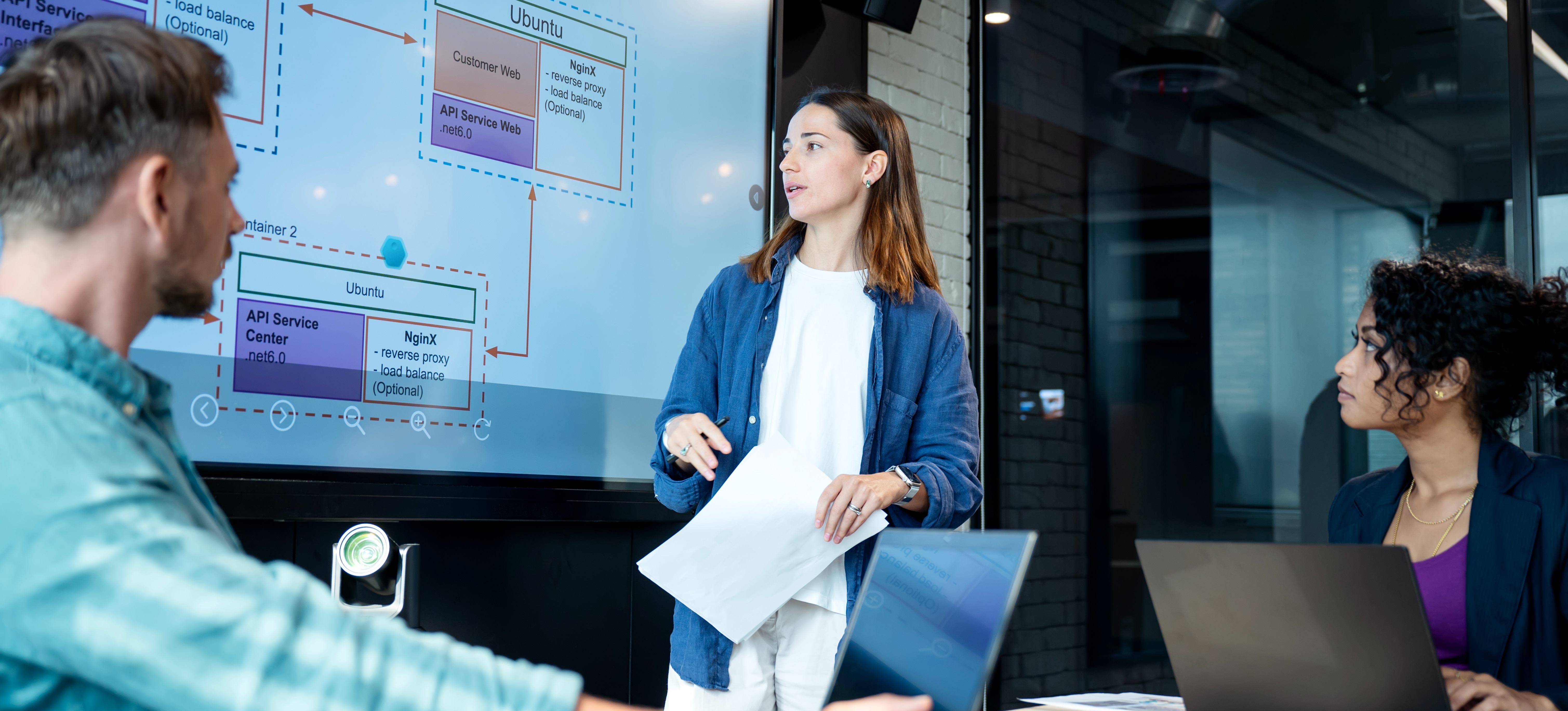 [Feature Image] An Agile coach reviews the workflow for the team’s current sprint in a conference room.
