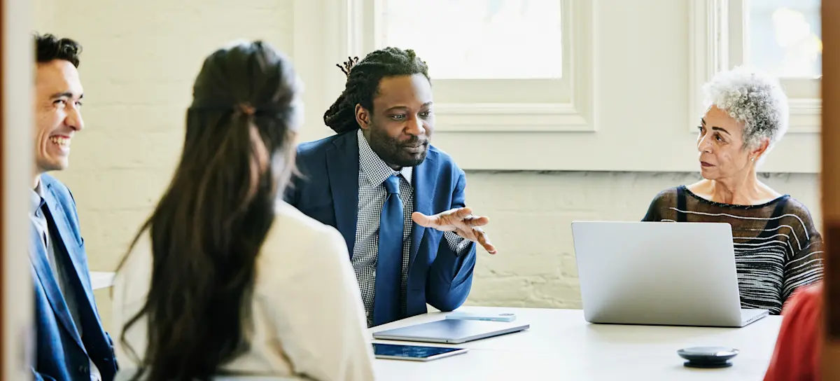 [Featured Image] Male businessman using a tablet explains tanh activation function to coworkers in breakroom