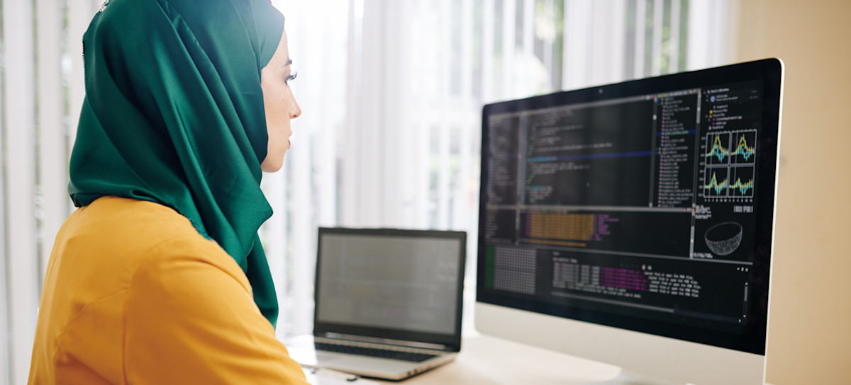 [Featured image] An ethical hacker takes notes of data charts from their desktop. 