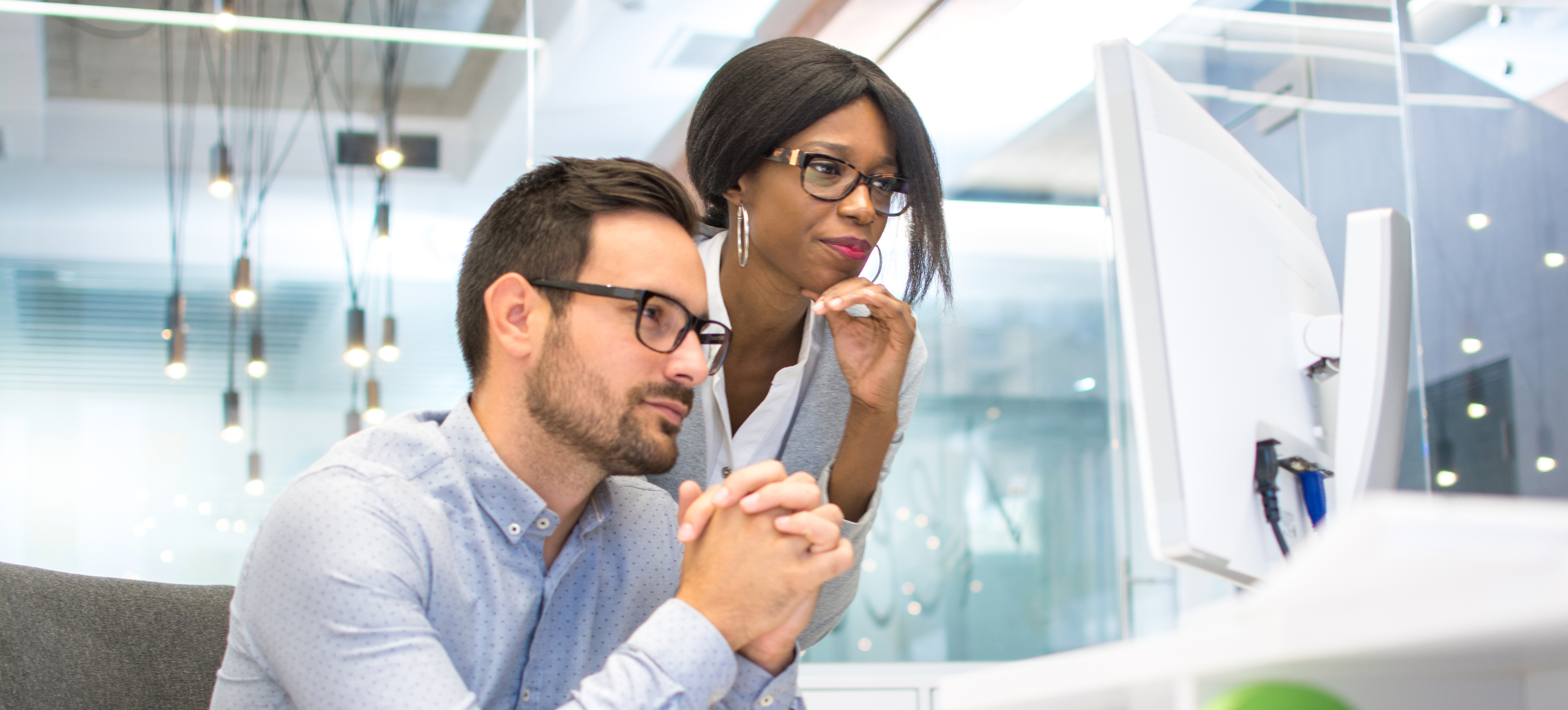 [Featured Image] Two data scientists look at a computer screen in their office and discuss Spark versus MapReduce.
