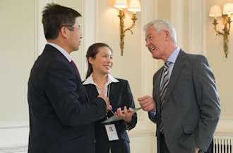 [Featured Image] Three government workers talking in a federal office.
