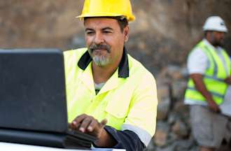 [Featured Image] A quarry manager looks at a laptop and uses photogrammetry to make important mining decisions. 