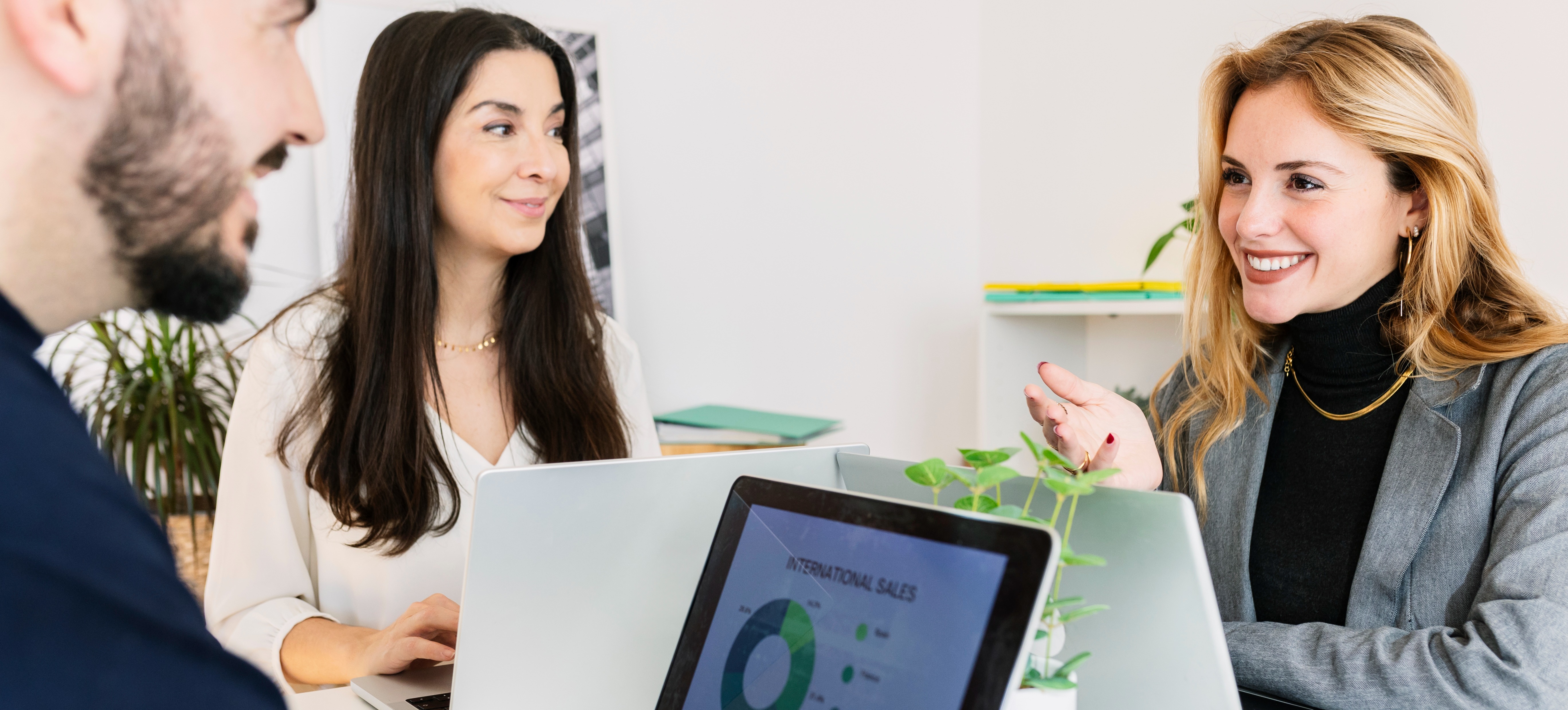 [Featured Image] Professionals collaborate on a project and discuss LangGraph with a laptop displaying an international sales graph.
