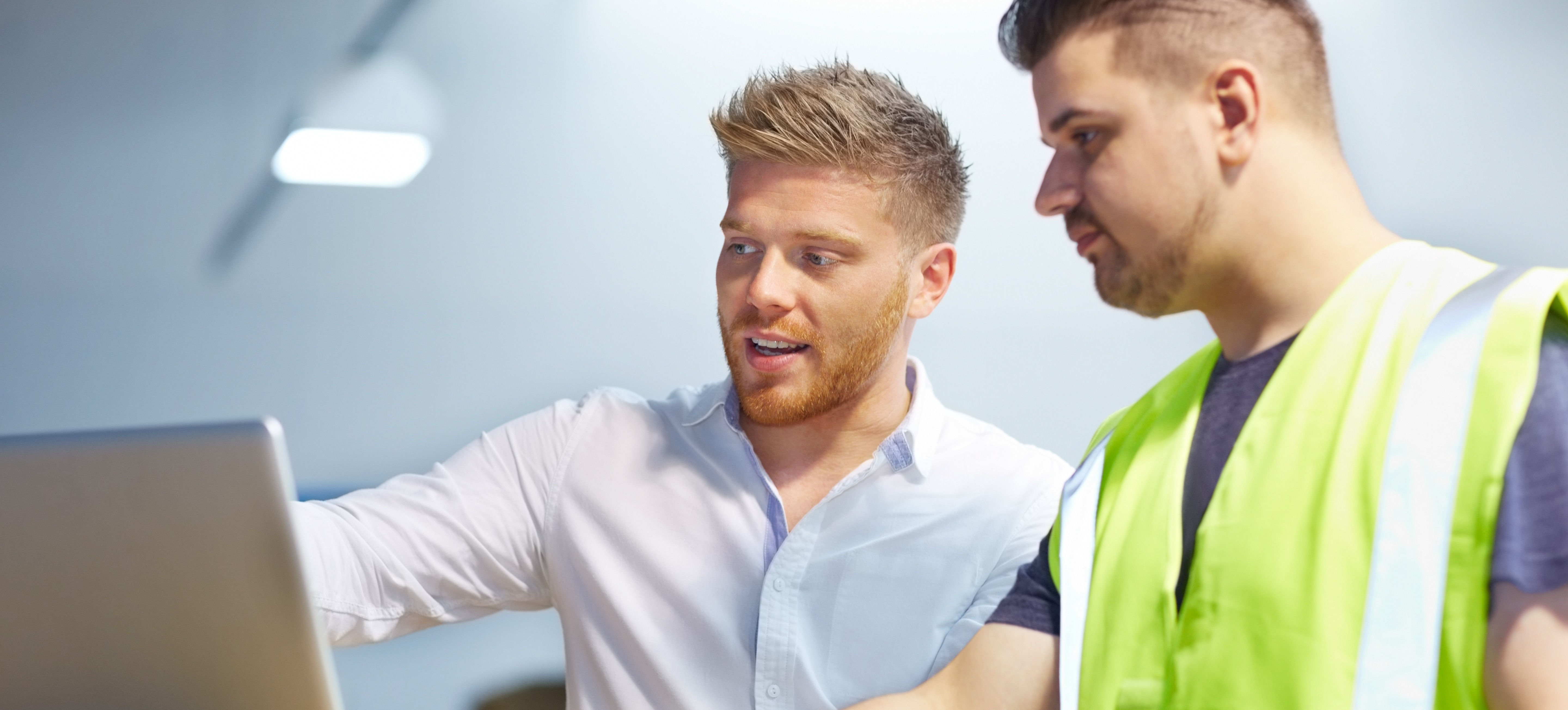 [Featured Image] A supply chain planner meets with a factory foreperson to discuss logistical planning. 