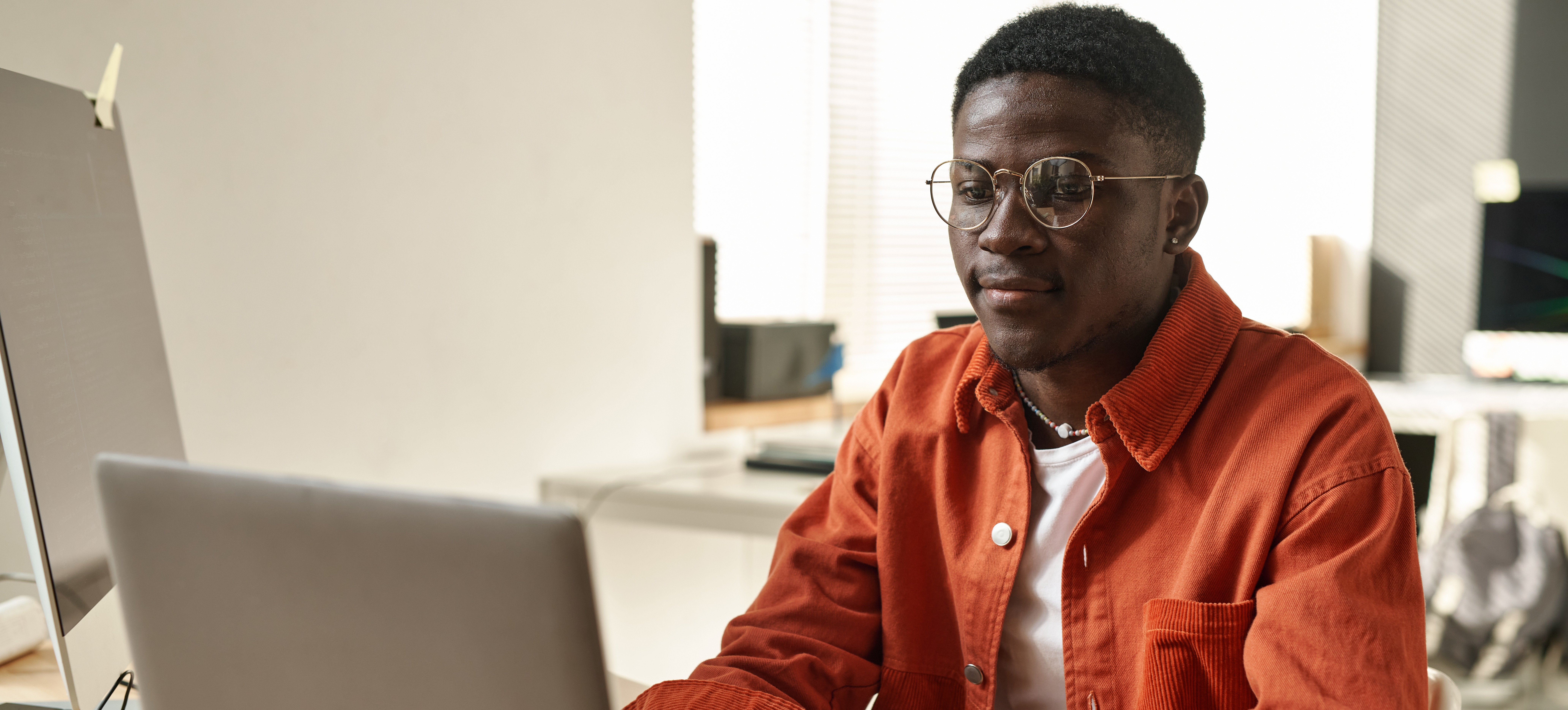 [Featured Image] A software engineer sits at a workstation, using containerization to simplify his job.
