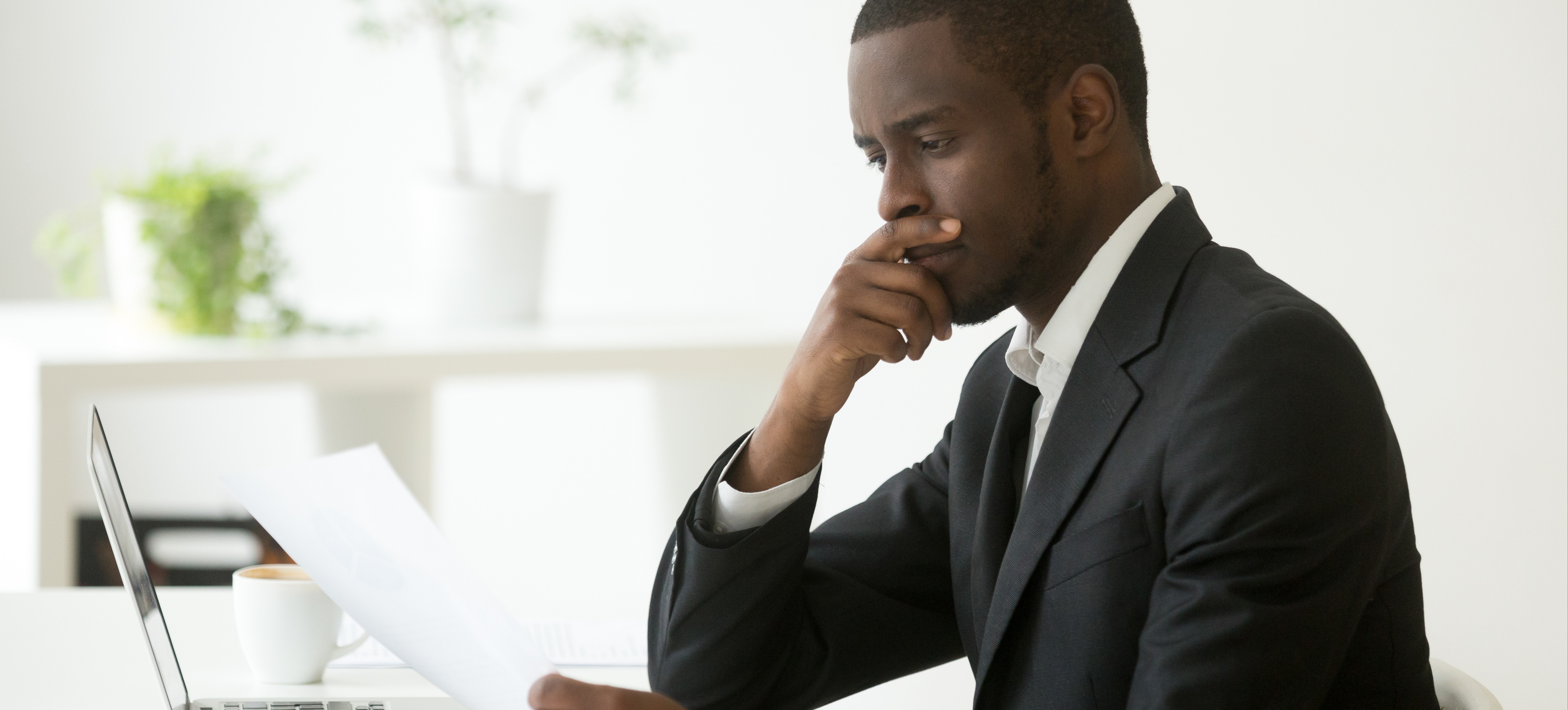 [Featured Image] A business professional is using analytical thinking as they read a document at their workspace.
