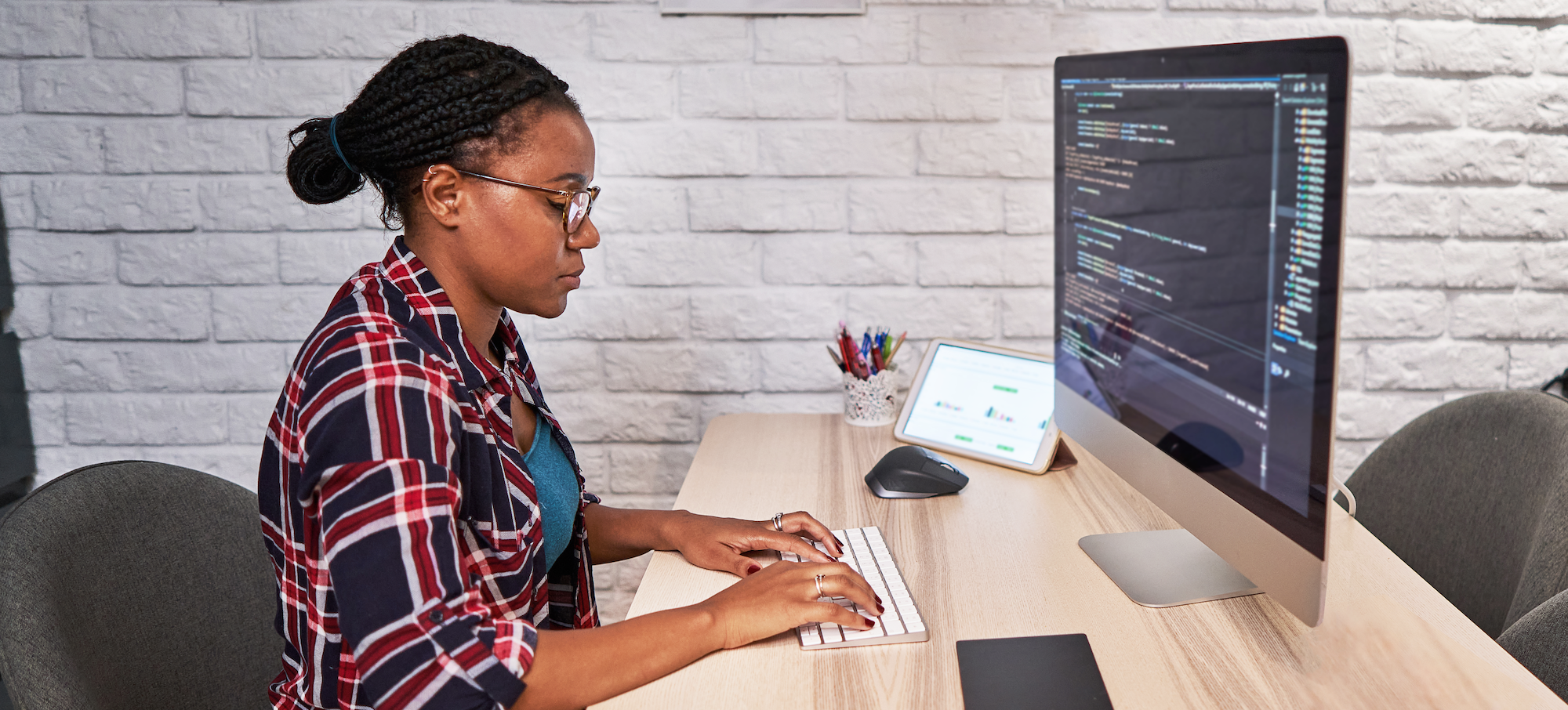 [Featured image] A data scientist in a plaid shirt sits at a computer and writes code.