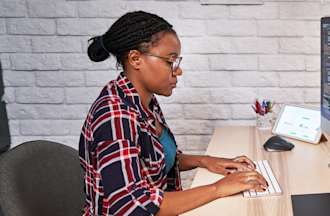 [Featured image] A person in a plaid shirt sits at a computer and writes code.