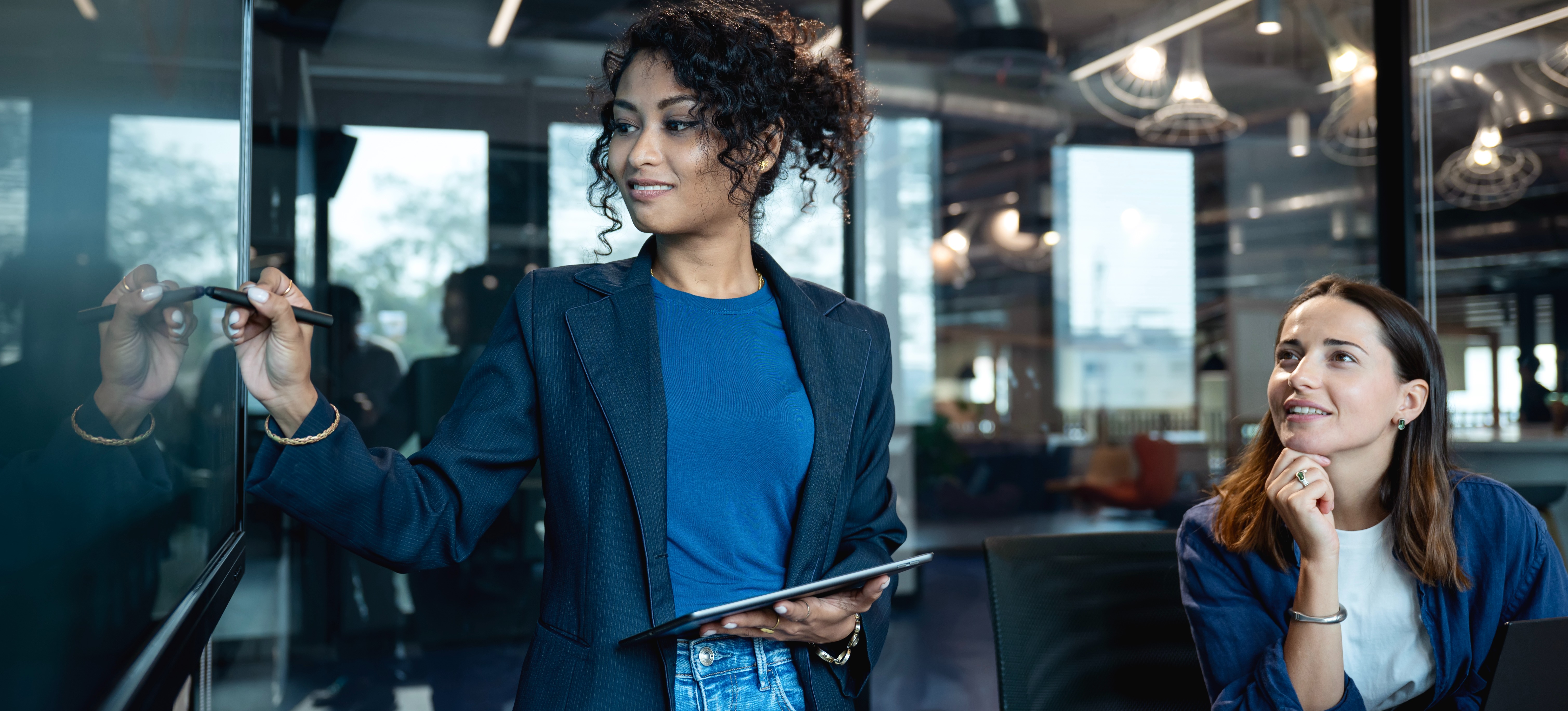 [Featured Image]: A person writes on a board as they meet with a team as part of an Agile product management framework.