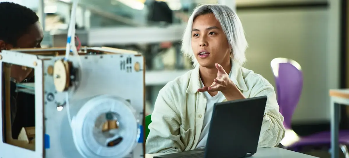 [Featured Image] A programmer uses the ChatGPT canvas feature as they talk to their colleague while sitting in front of a laptop.
