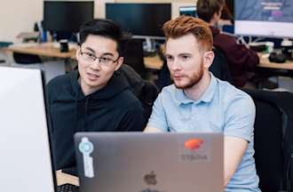 [Featured Image] A business intelligence manager and a colleague are working at a computer, looking at a business intelligence dashboard.