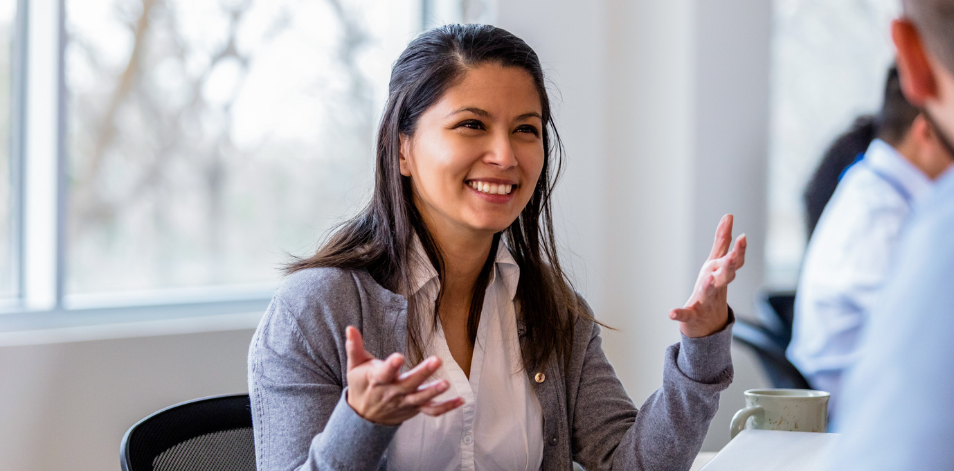 [Featured image] A person working in healthcare administration speaking animatedly with their colleague.