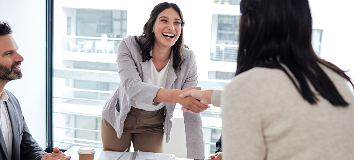 [Featured Images] A happy person standing up in an office at a table shaking the hand of another person who has finished asking Hadoop interview questions with a coworker.
