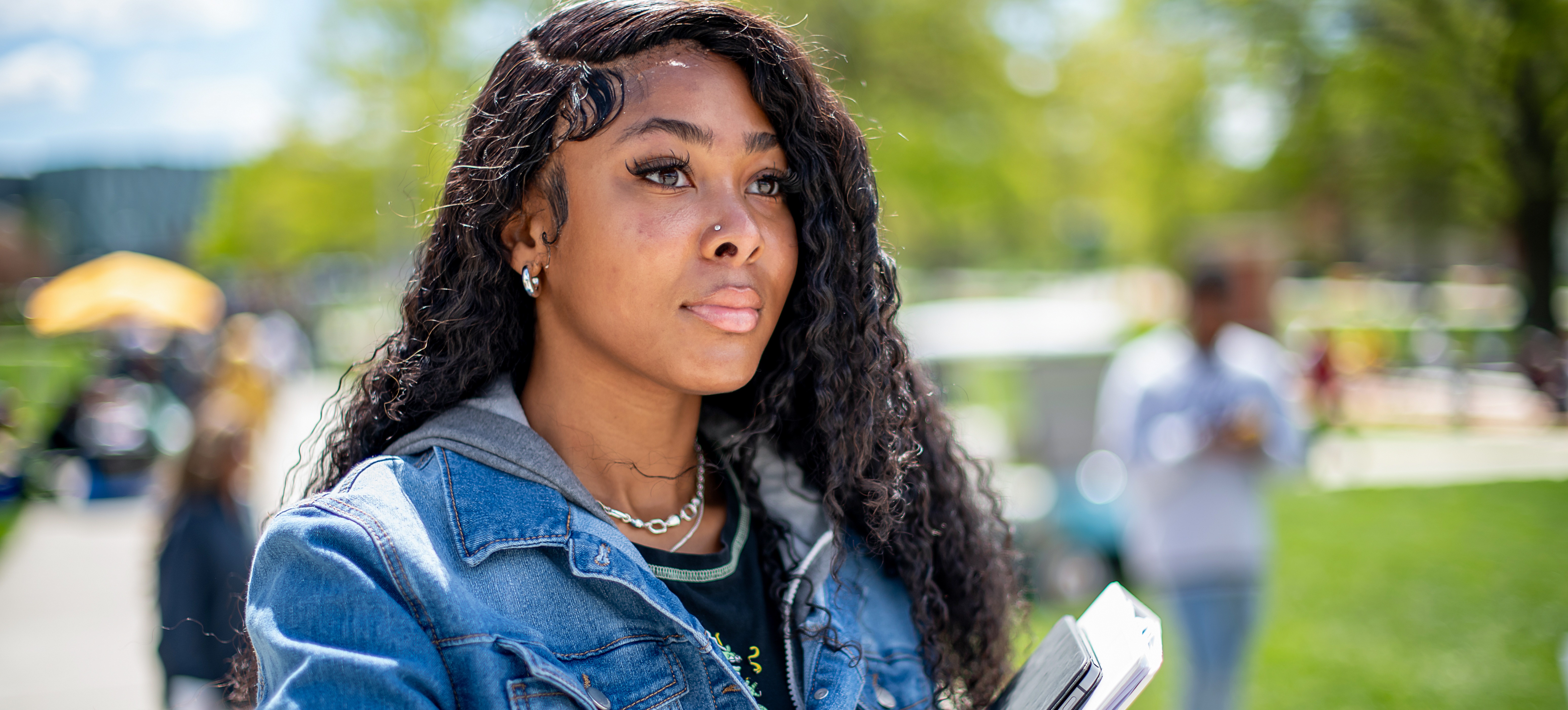 [Featured Text]: A young person carries books as they walk on a college campus and reflects on what does HBCU stand for.
