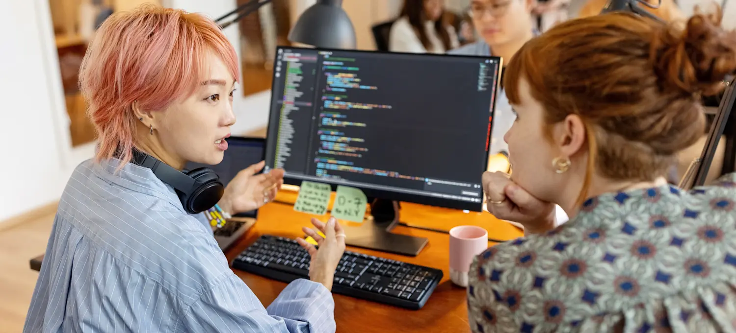 [Featured Image] Two software developers discuss using Kubernetes for containerized management of applications.
