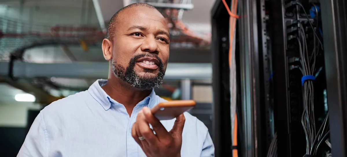 [Featured Image] A person receiving a network technician salary is on a phone call while in a server room.
