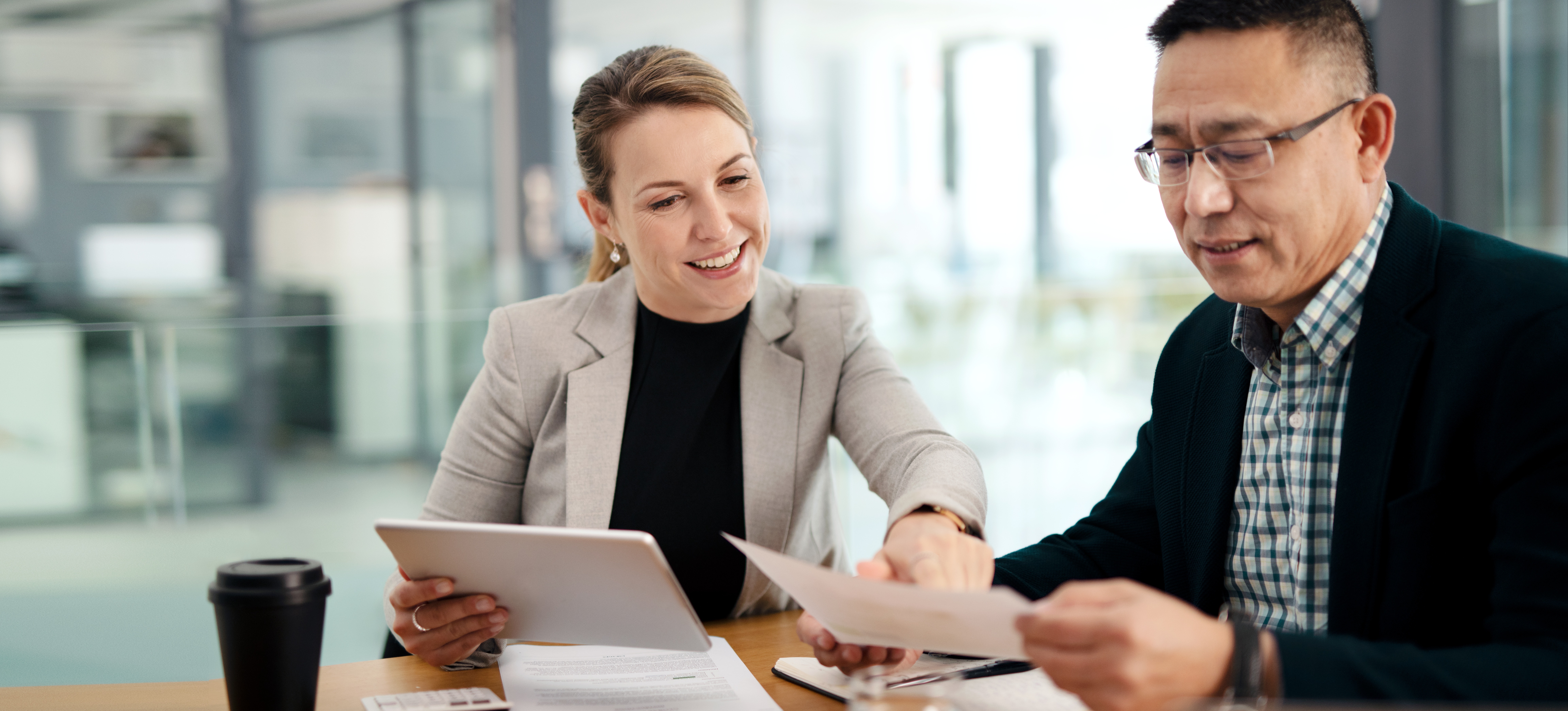 [Featured Image] A tax accountant explains tax forms to their colleague in an office space.
