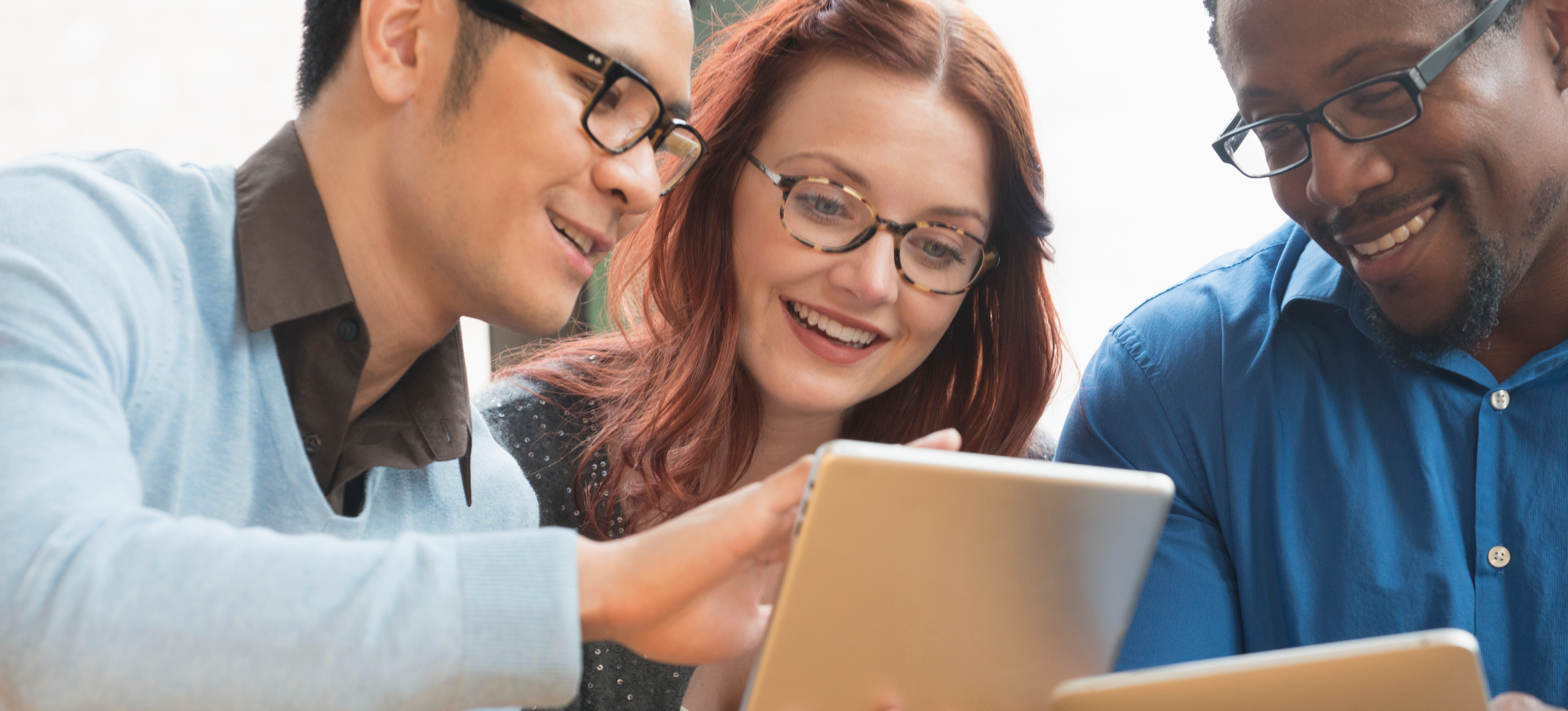[Featured Image] Three co-workers are sending files through their communication network protocols on digital tablets.