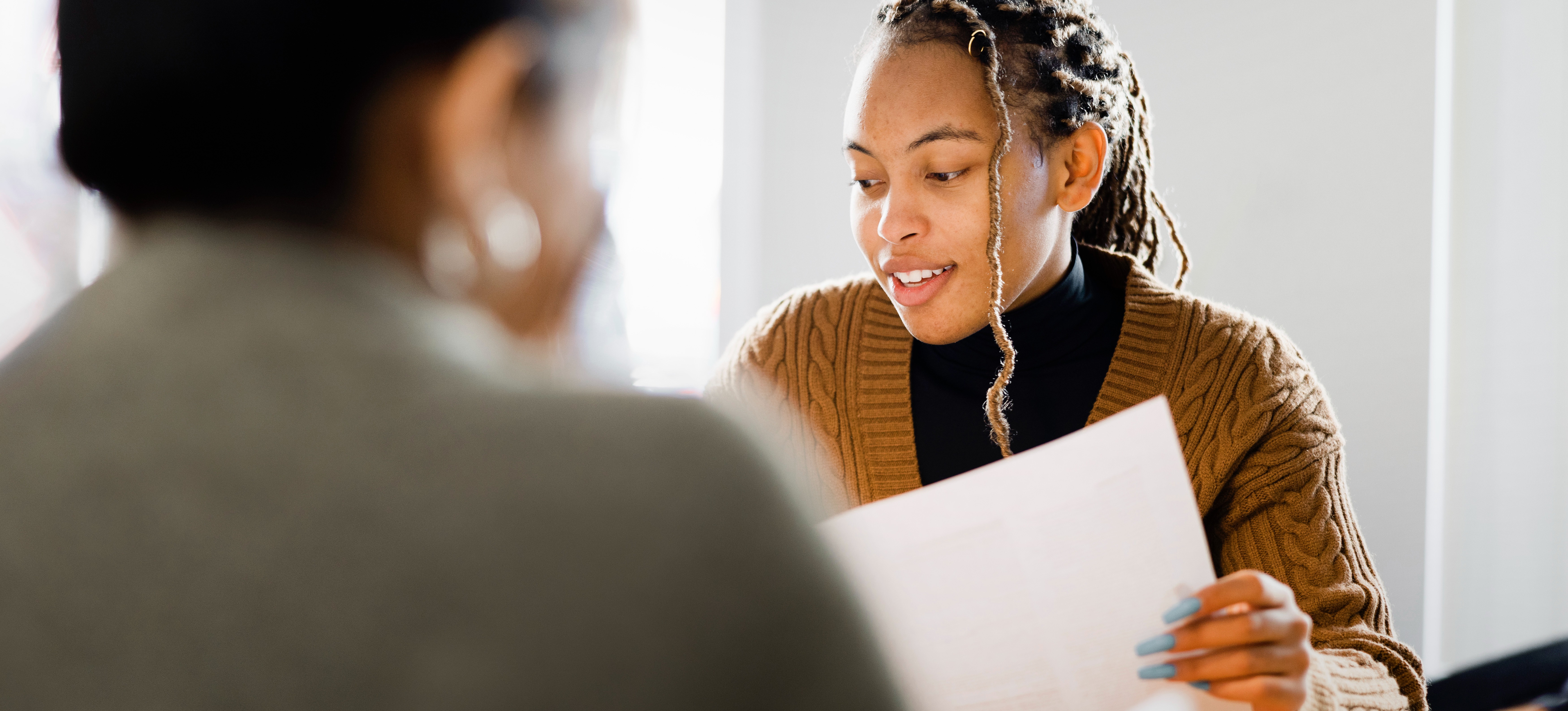[Featured image] A person in a black shirt and brown sweater reads over the cover letter for an internal position that's hiring.