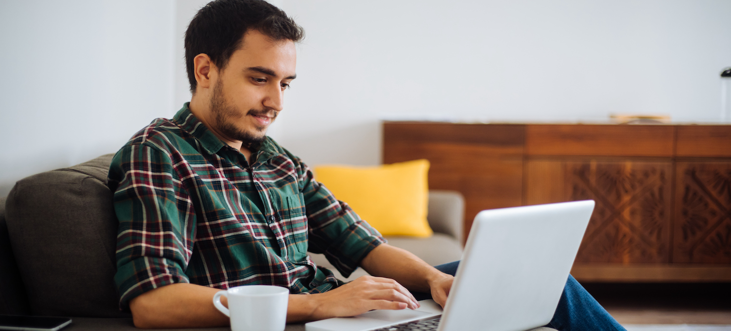 [Featured image] A person sits in an armchair working on a laptop while completing their business management degree.