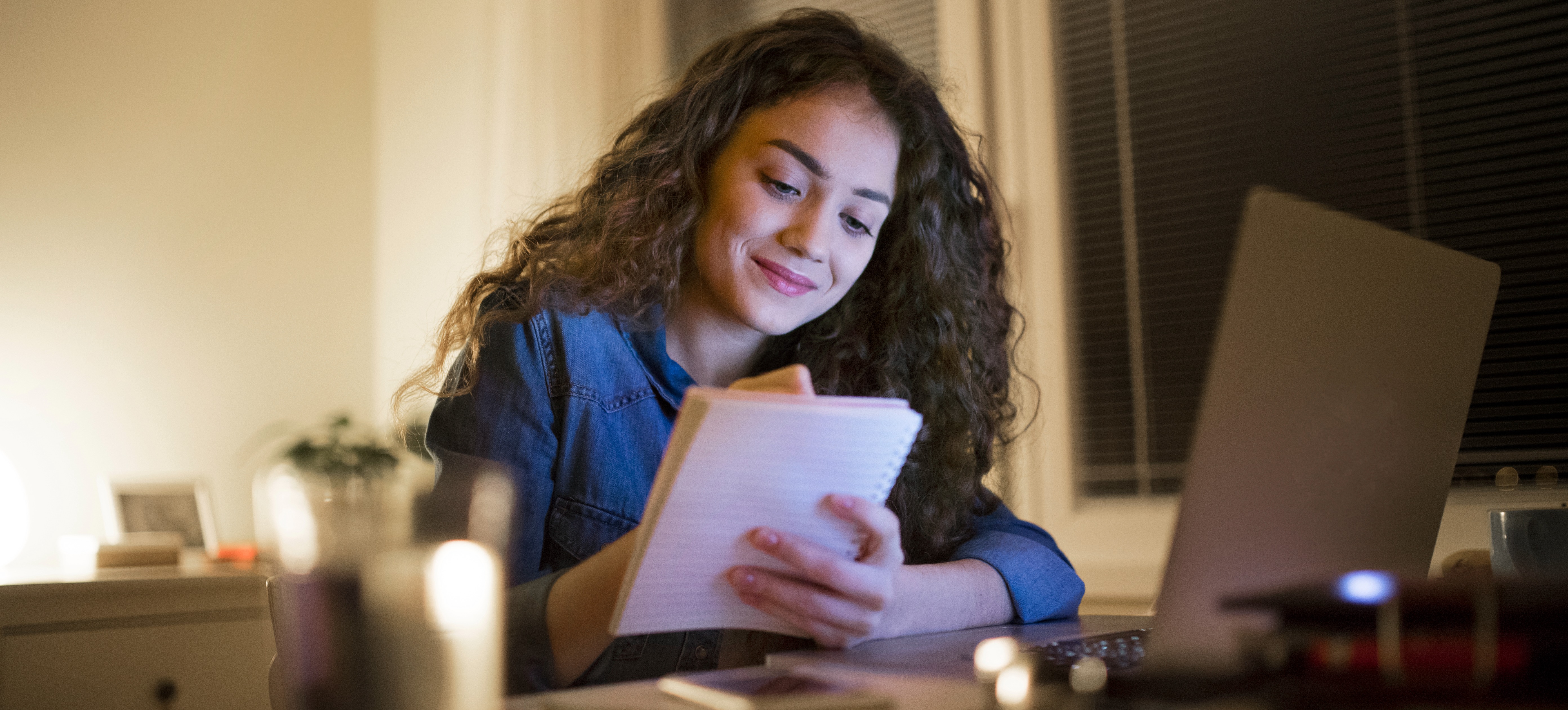 [Featured image] Woman sits at her desk, jotting down notes about her Shopify inventory in her notebook.