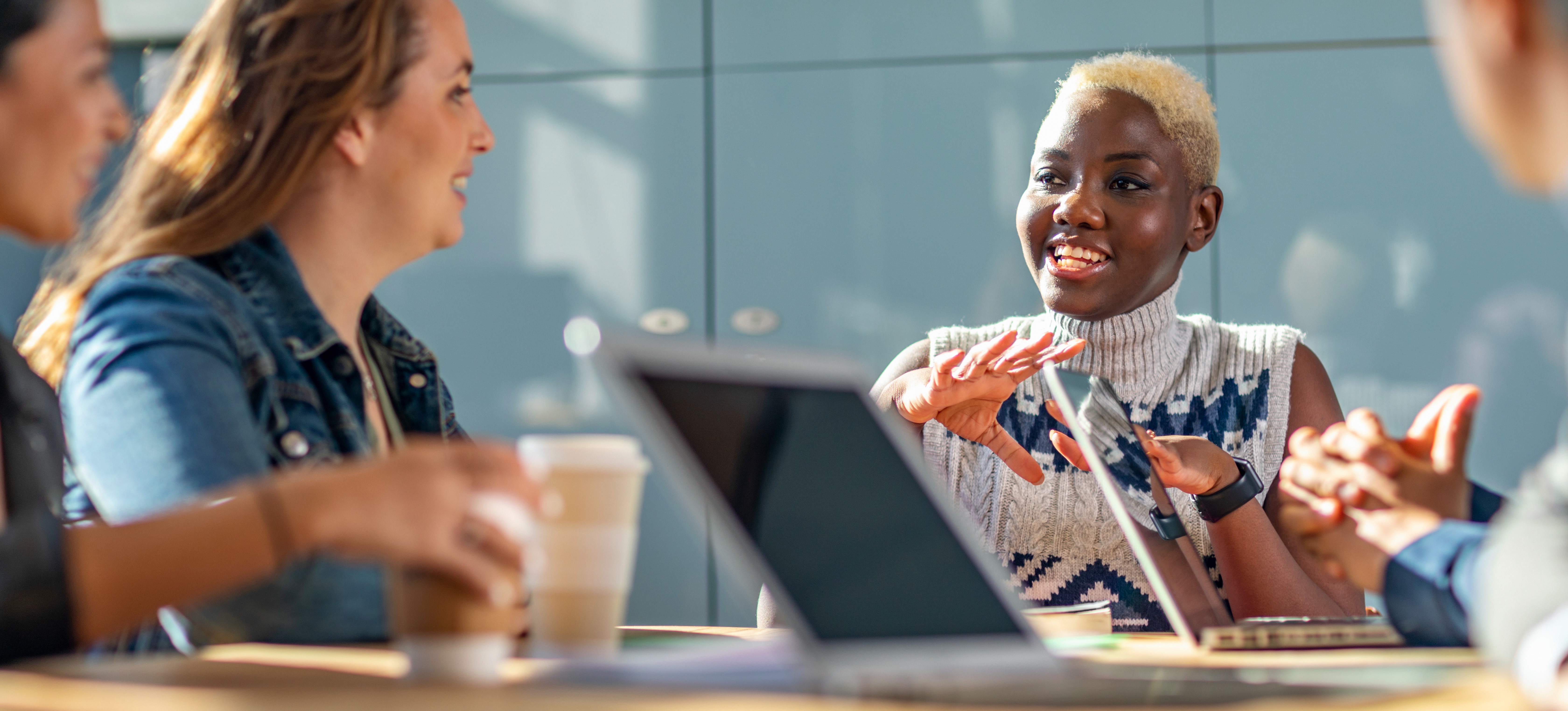 [Featured Image] A group of IT professionals meets in a conference room with laptops to discuss how to implement zero trust security in the cloud for their organization. 
