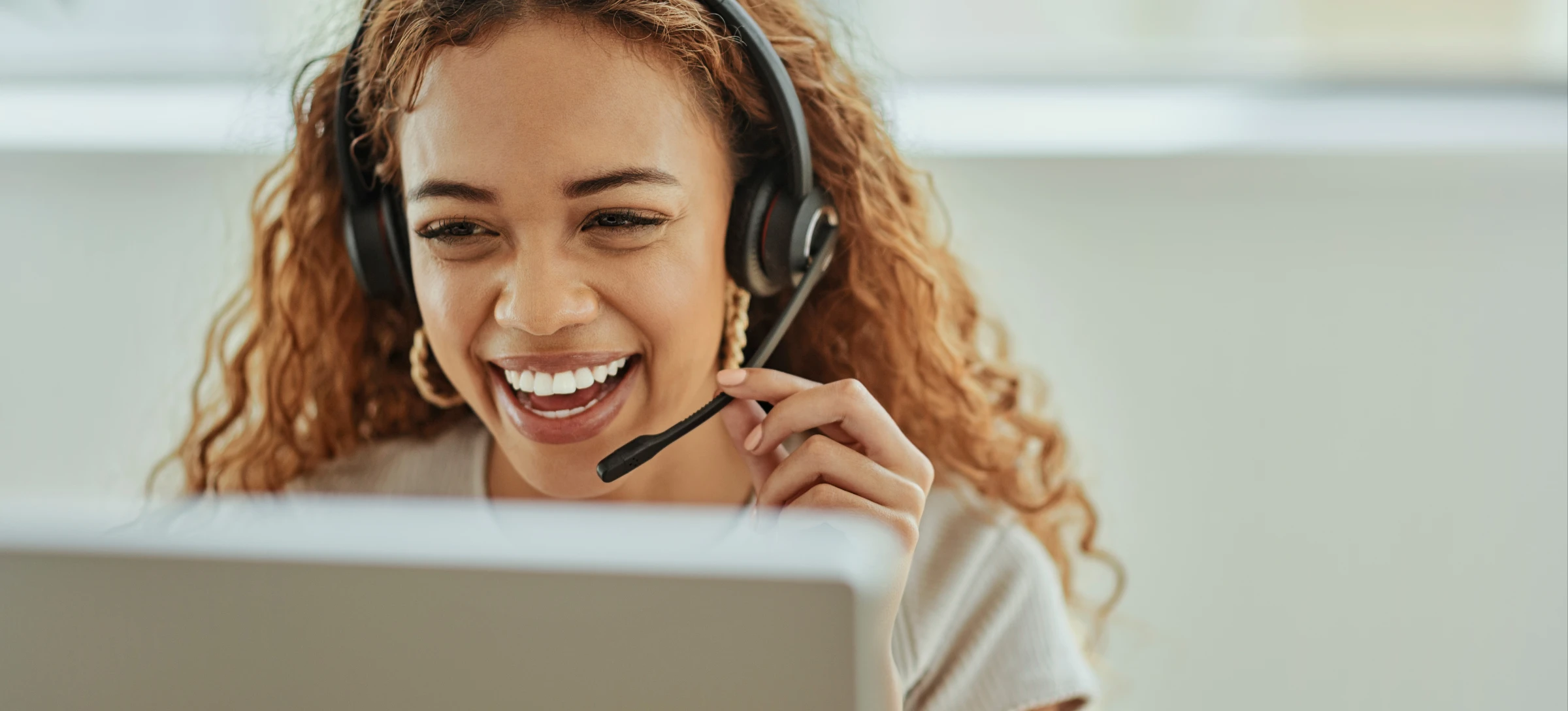 [Featured Image] A receptionist in the service industry smiles while talking to a client and providing excellent customer service over the phone. 
