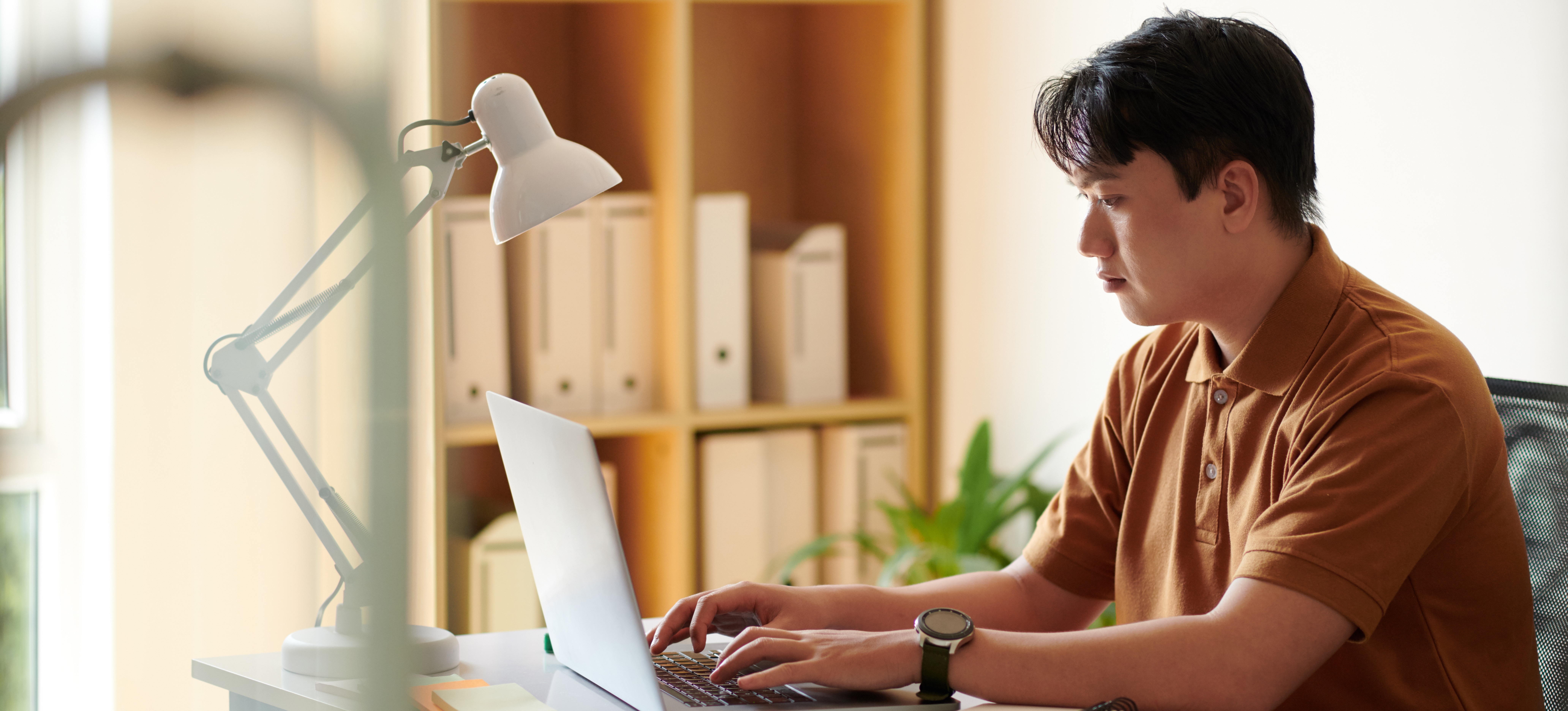 [Hauptbild] Ein Geschäftsmann, der eine Ausbildung zum DevOps-Ingenieur absolviert hat, sitzt an seinem Schreibtisch, arbeitet an einem Laptop und hilft seinem Softwareentwicklungsteam bei der Planung von Projektanforderungen und Infrastruktur.