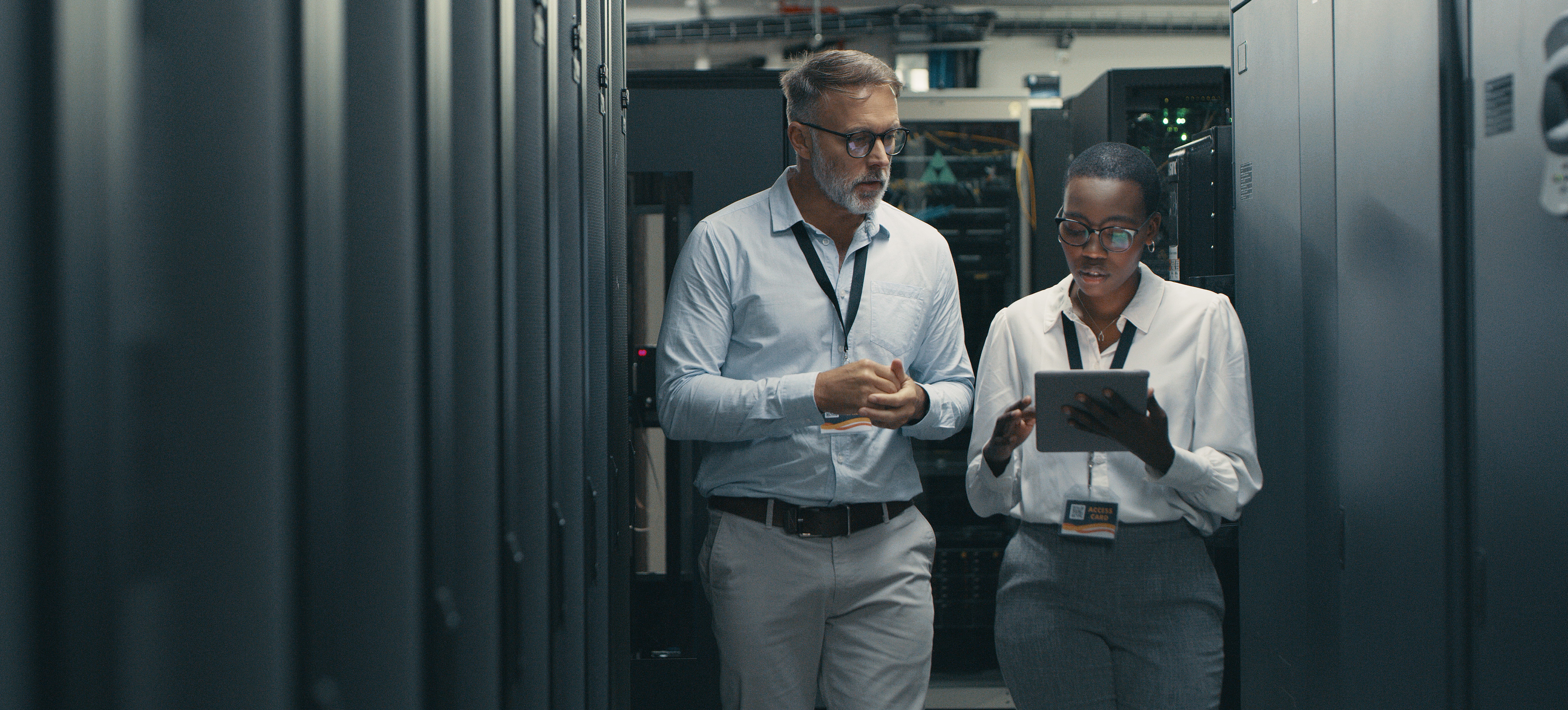 [Hauptbild] Zwei in einem Rechenzentrum arbeitende, für Cybersicherheit zertifizierte Experten diskutieren verschiedene Arten von Firewalls.