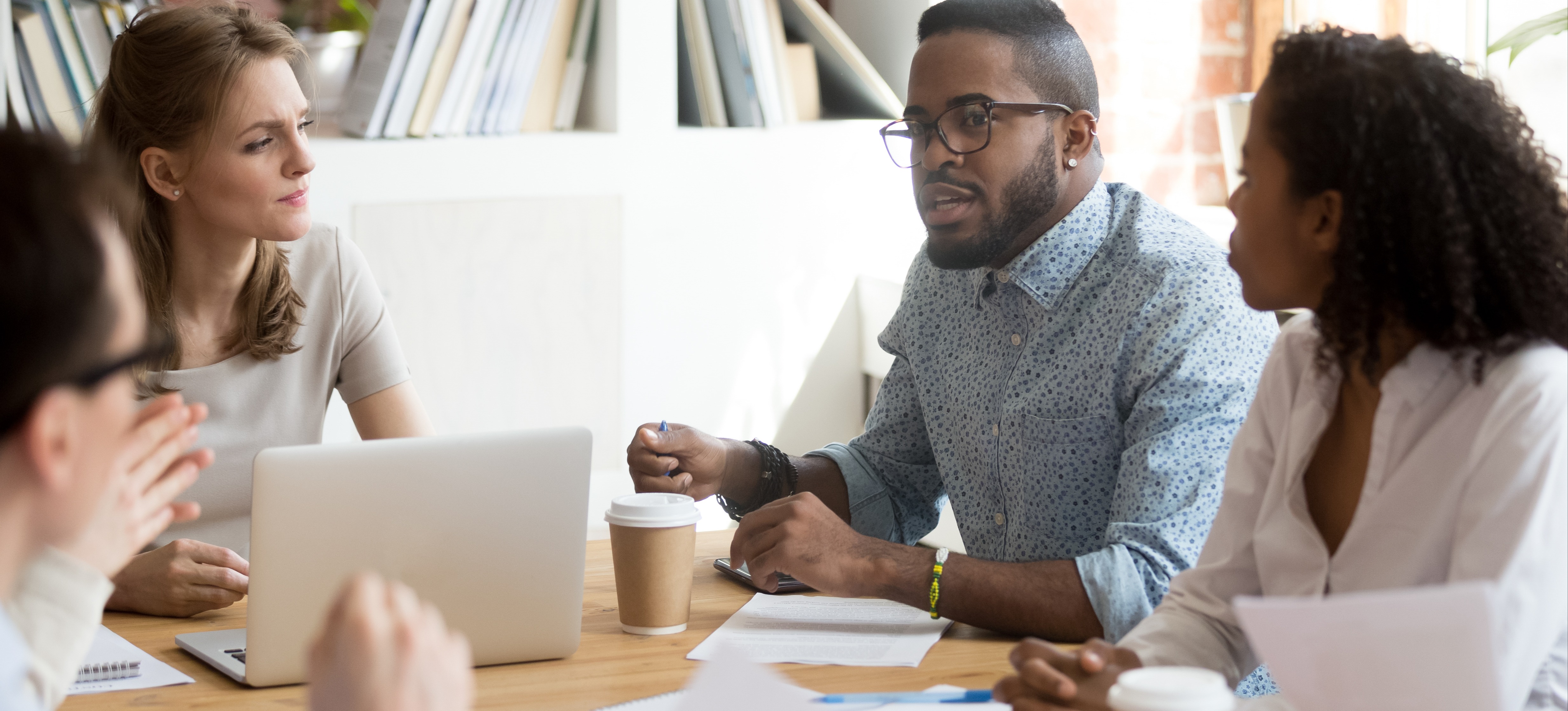 [Featured Image] A group of marketers meet in a conference room and talk about the way AI disrupts their industry.
