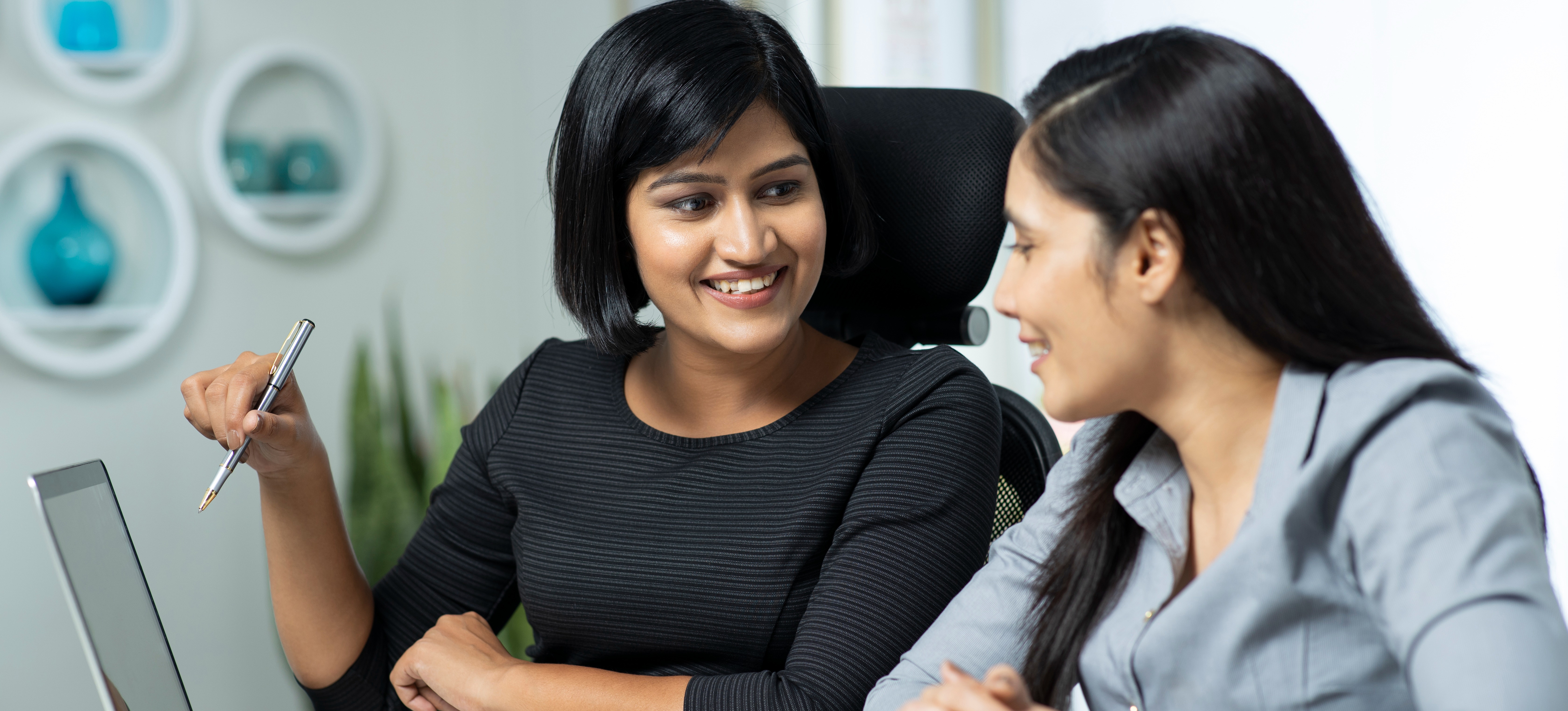 [Featured Image]: Two women engage in a conversation as they discuss business objectives as part of the company's strategic management plan.
