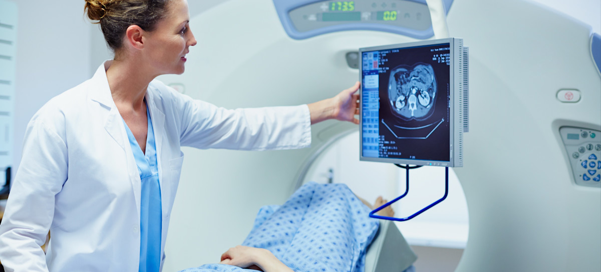 [Featured Image] A physician standing next to a child who is lying on a hospital bed at the entrance to an MRI machine examines medical imaging on a screen aided by image classification.
