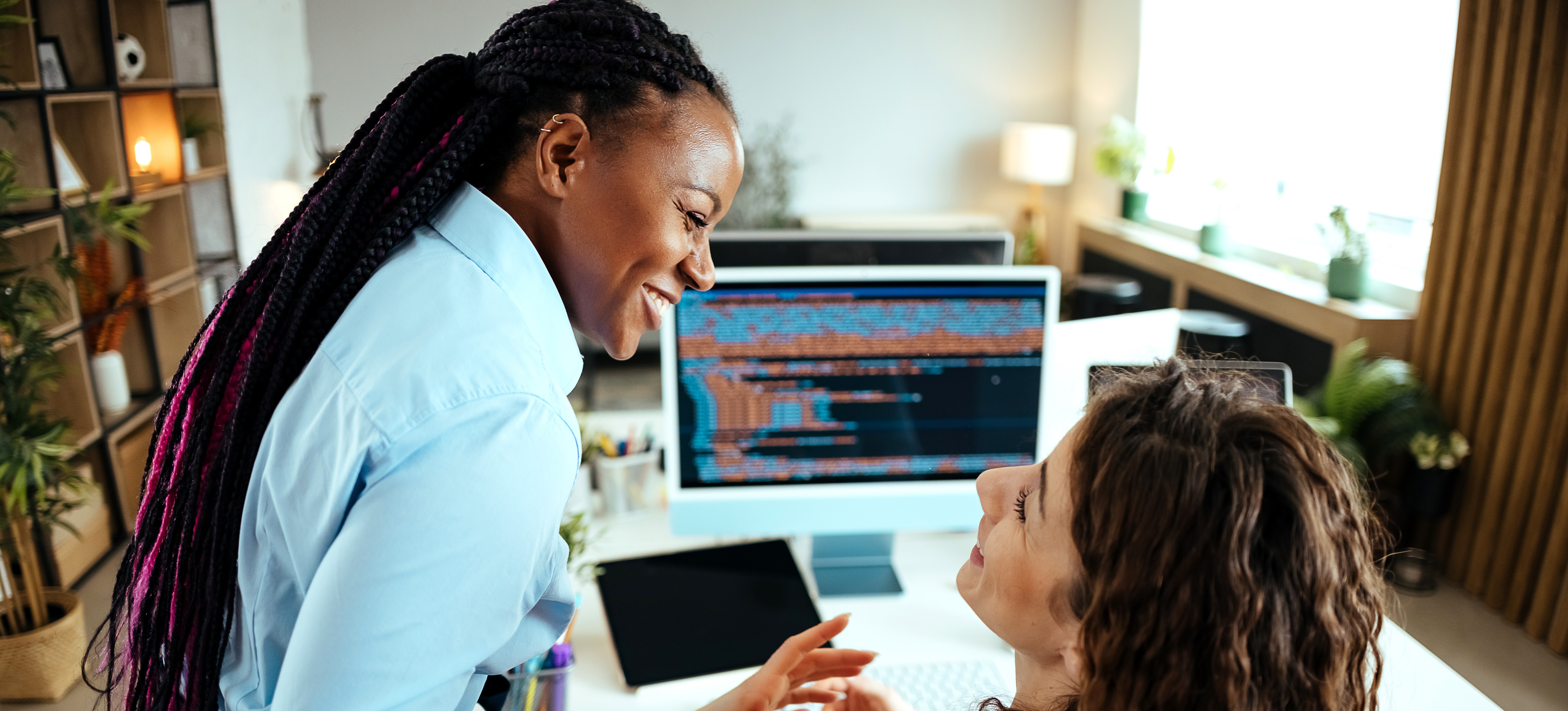 [Featured Image] NLP developers collaborating on a new project, reviewing code on a laptop while sharing a light moment in a tech workspace.
