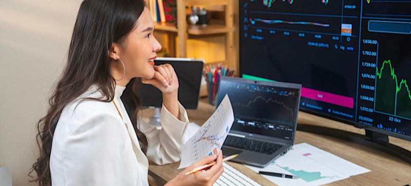 Featured Image: A businessperson is sitting at their desk, looking at a computer monitor that shows different types of correlations related to the stock market.