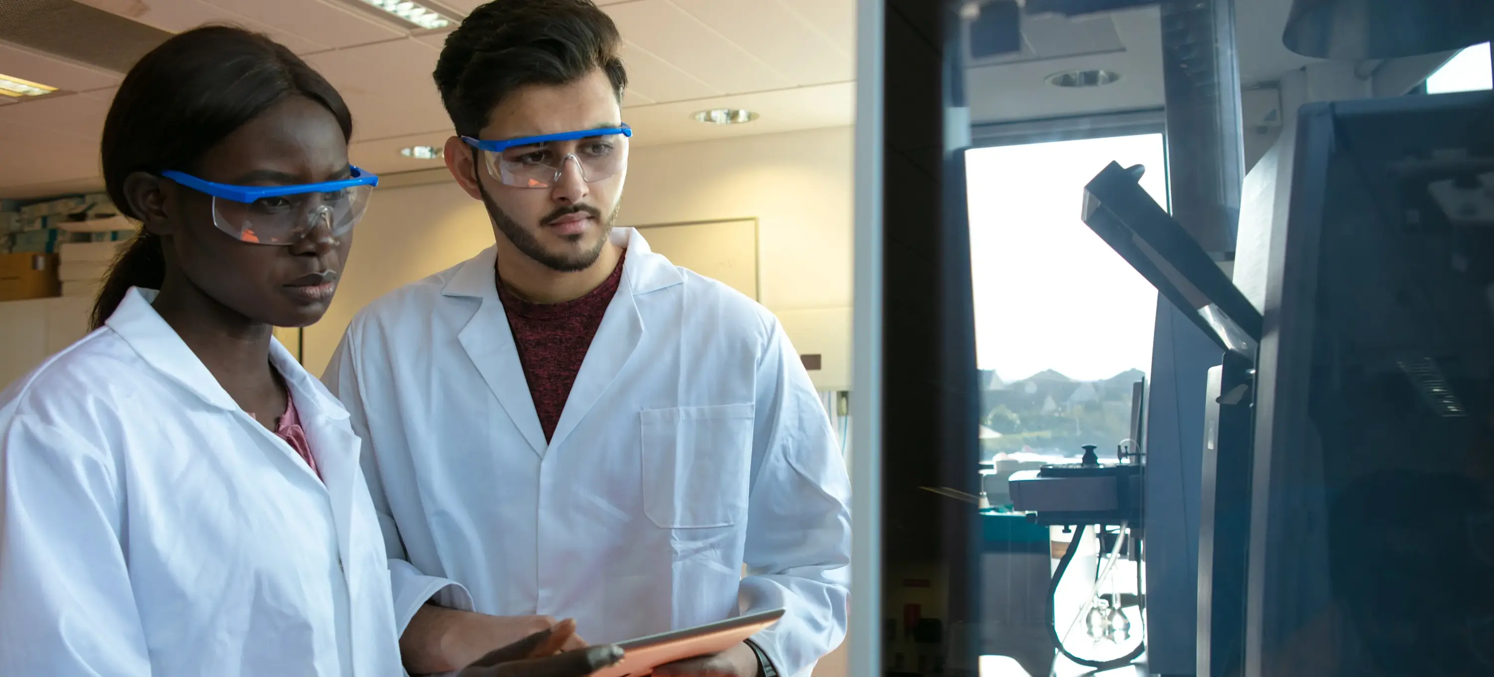 [Featured Image] Two health informatics workers examine data on a machine