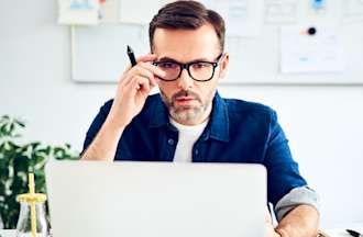 [Featured Image] A man wearing glasses works on a laptop computer.