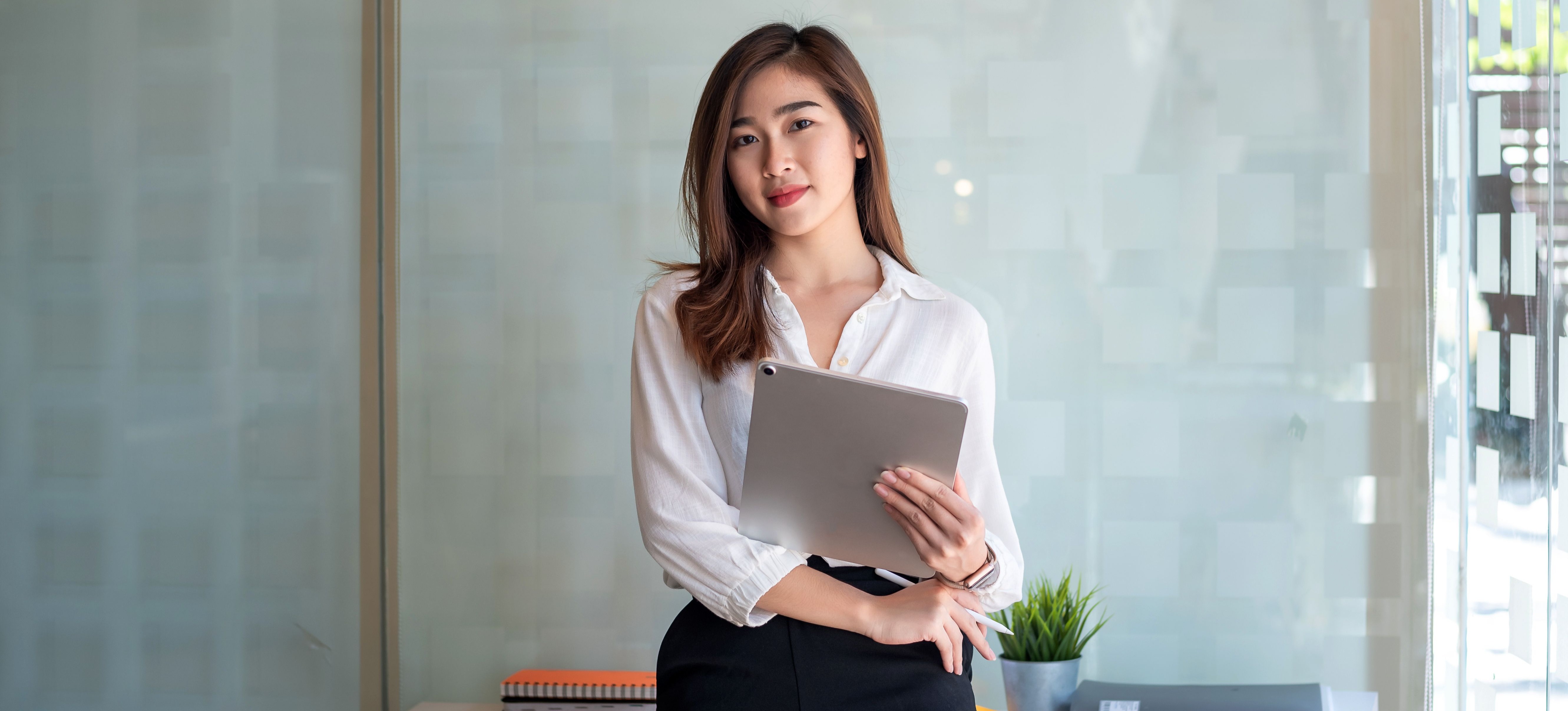 [Image en vedette] Une femme en tenue de travail décontractée tient une tablette et un stylo.