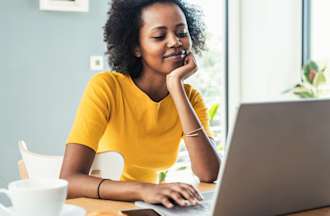 [Featured Image] A certified data professional sits at her laptop at home and researches new career paths she can take with a new certification.
