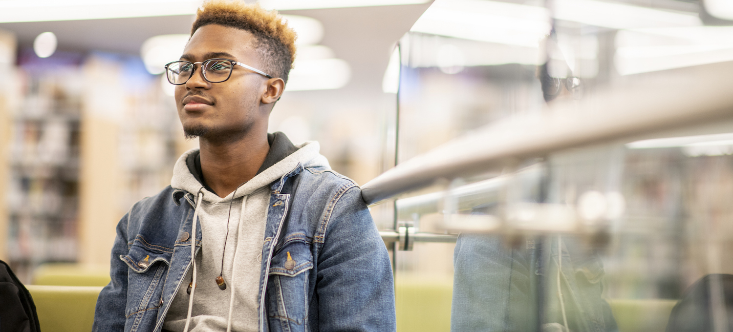 [Featured image] A person with glasses sits in a library learning about when college decisions come out.