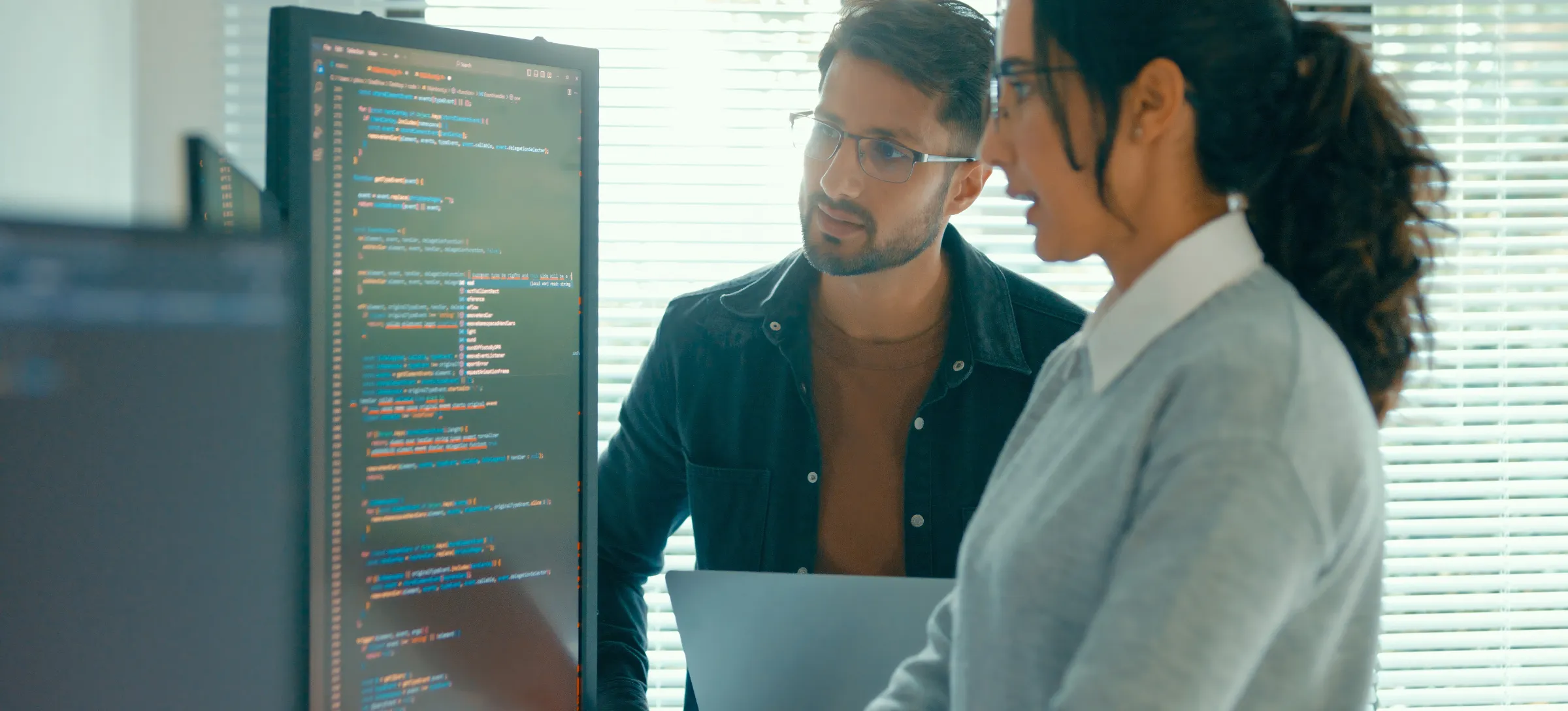 [Featured Image] Two network security engineers collaborate while troubleshooting a web development project to enhance cybersecurity. 
