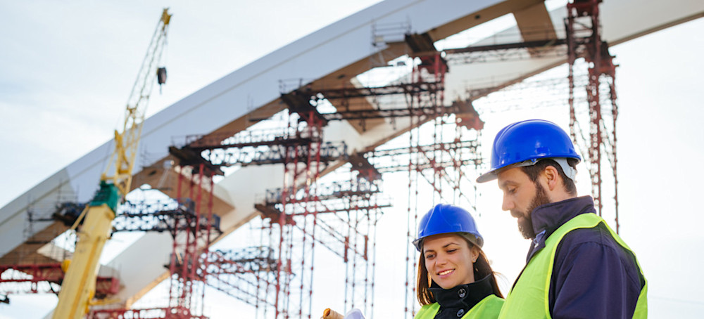 [Featured Image] Two construction management professionals discuss a job site. 