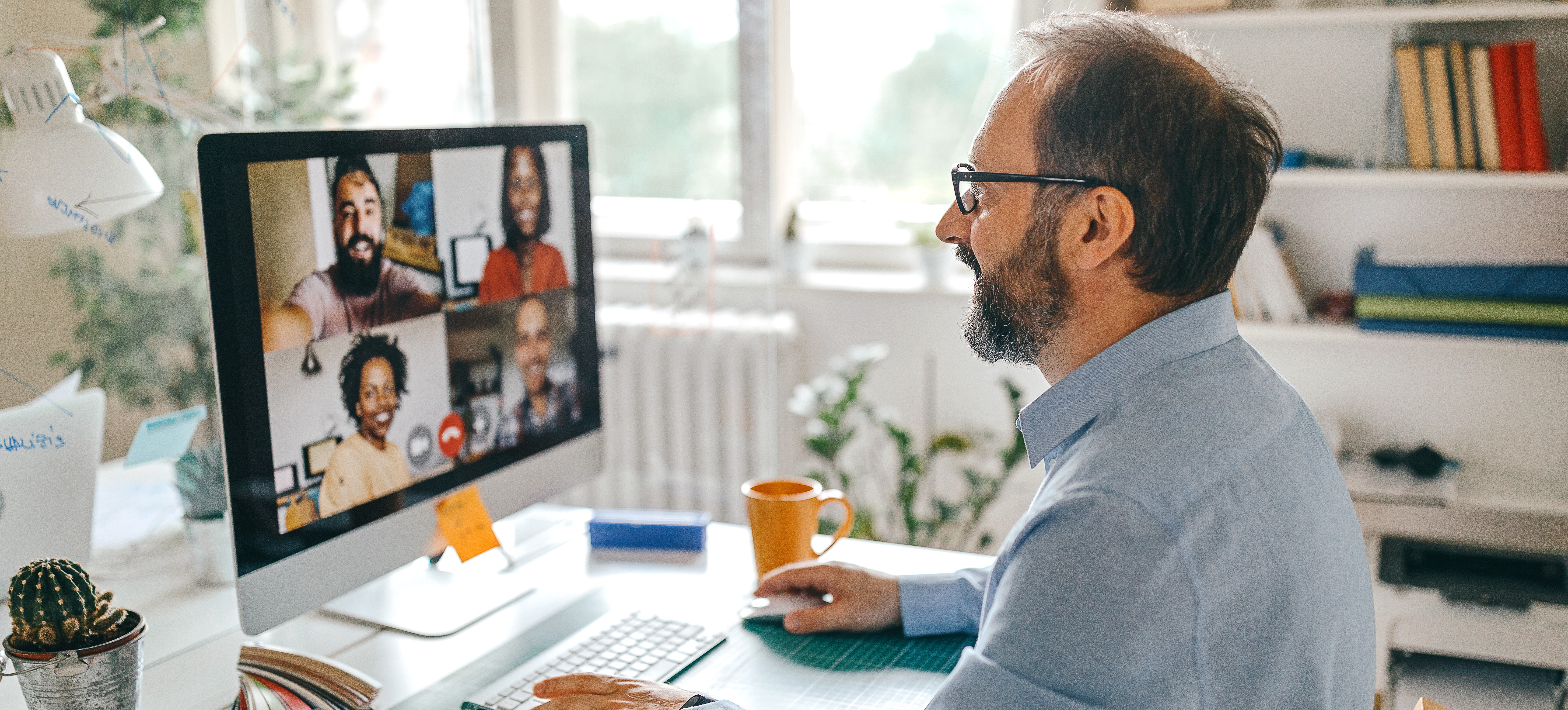 [Image en vedette] Un directeur qui sait gérer des équipes à distance organise une vidéoconférence avec ses collègues depuis son bureau à domicile.