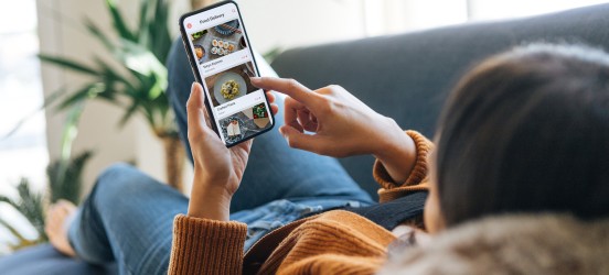 [Featured image] A mobile customer lying on a sofa converts after seeing a call to action on her cellphone.