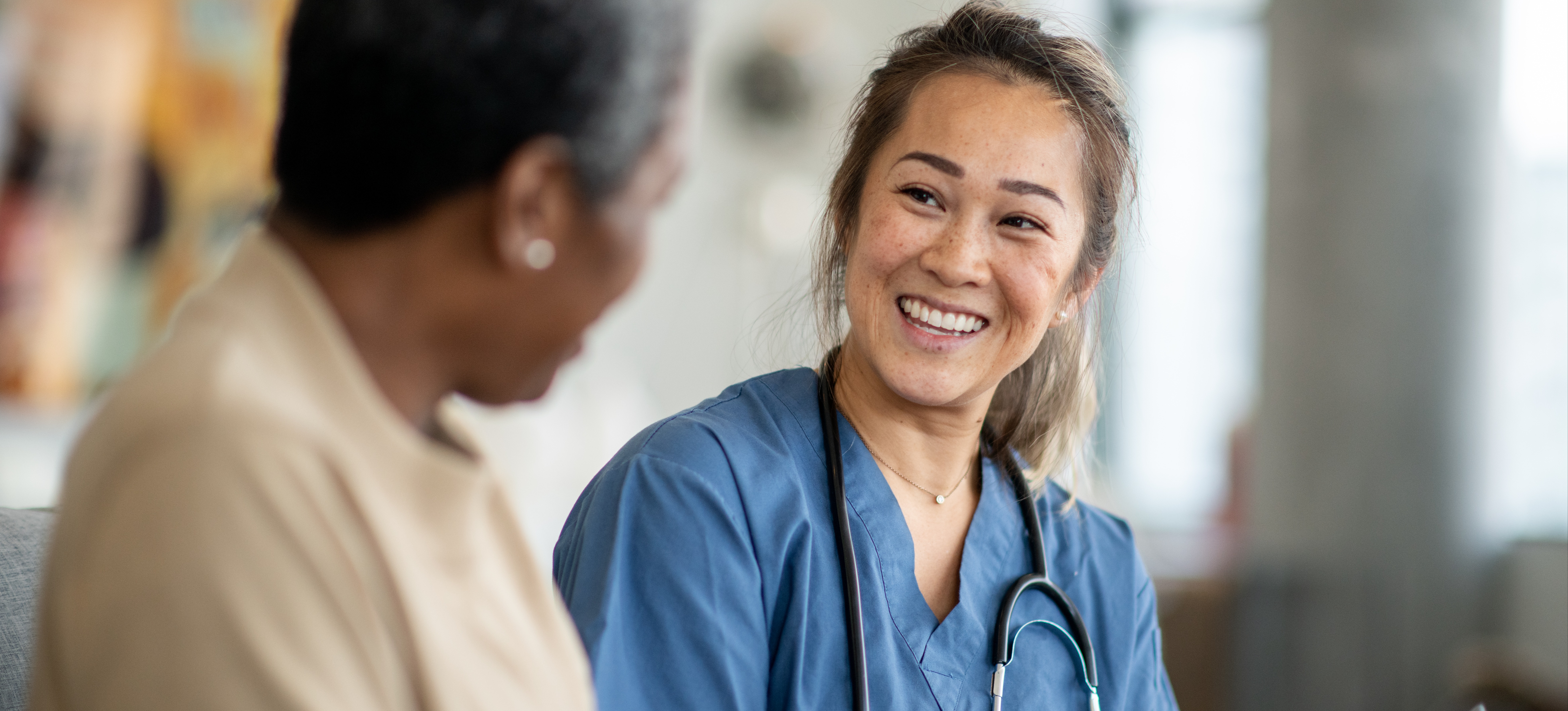 [Featured Image] A registered nurse discusses health care with a patient at a health clinic.