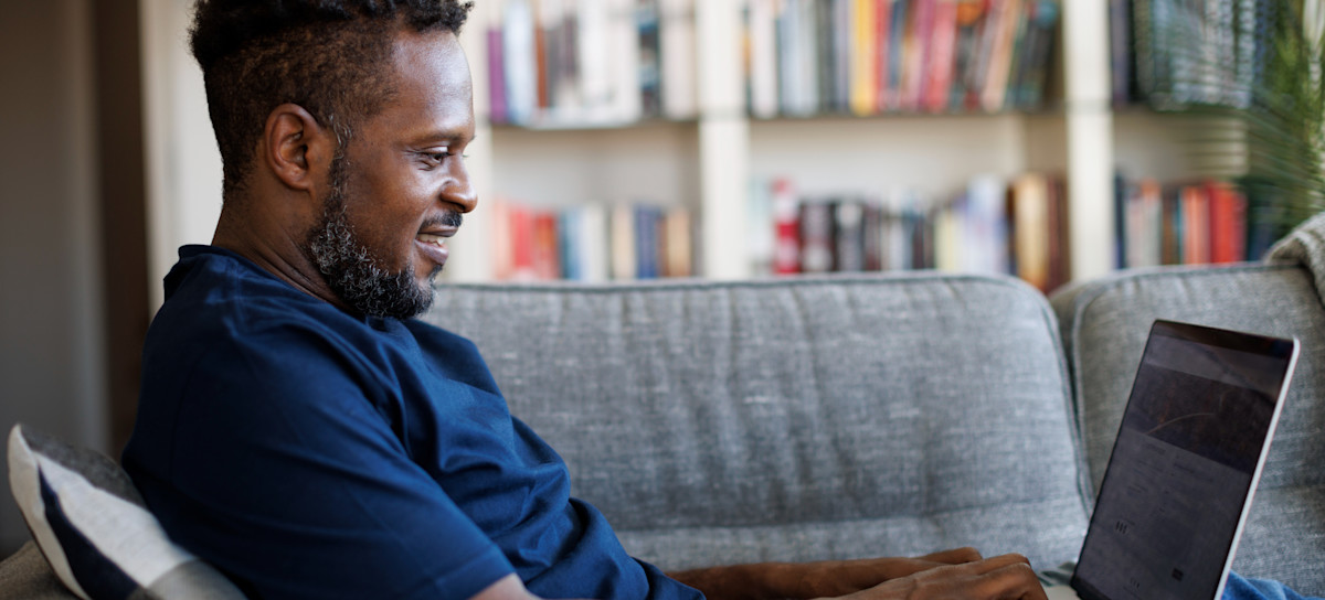 [Featured image]: A person sitting on a sofa smiles as they type on a laptop and learn how sites earn money.
