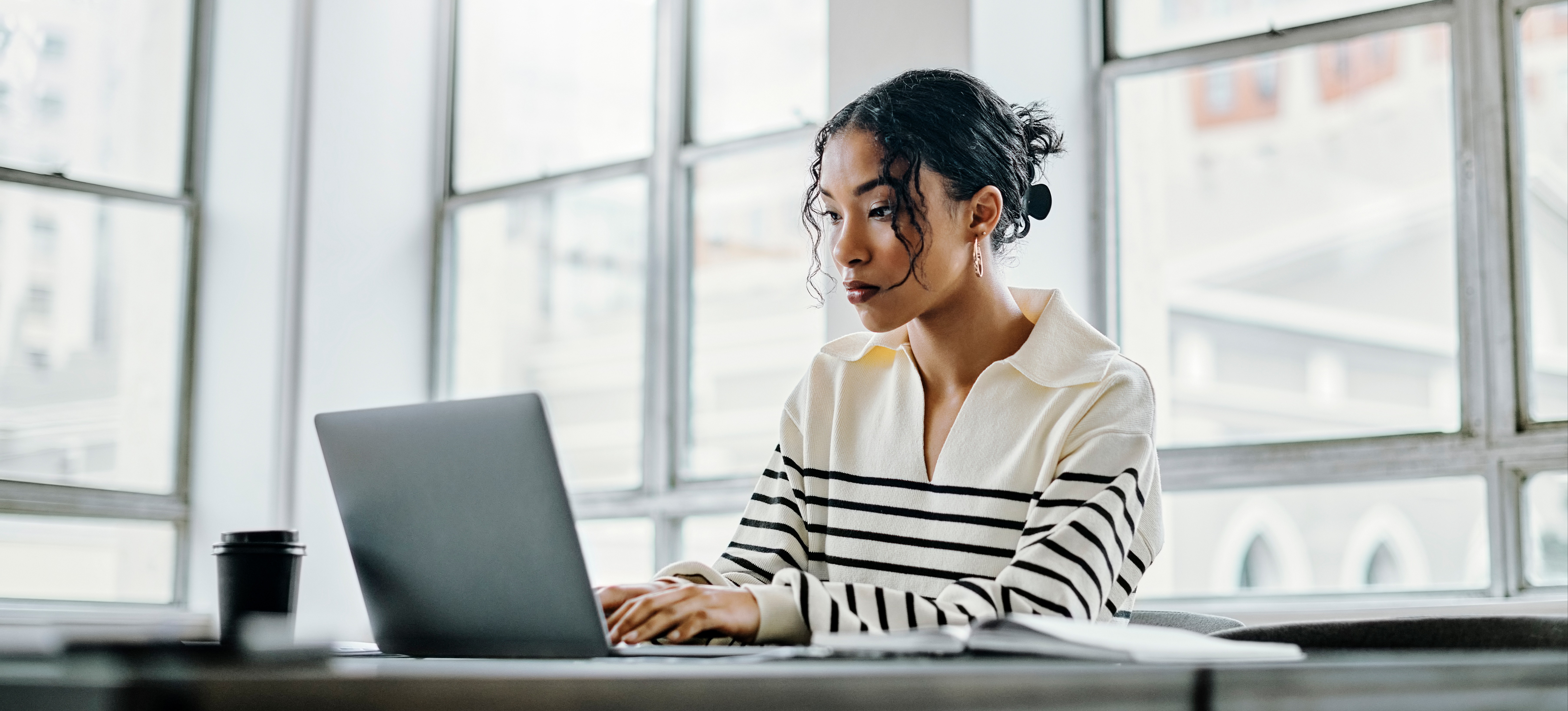 [Featured Image] A young learner sits in a sunny, windowed room and researches the highest-paying entry-level jobs in their chosen field on their laptop.
