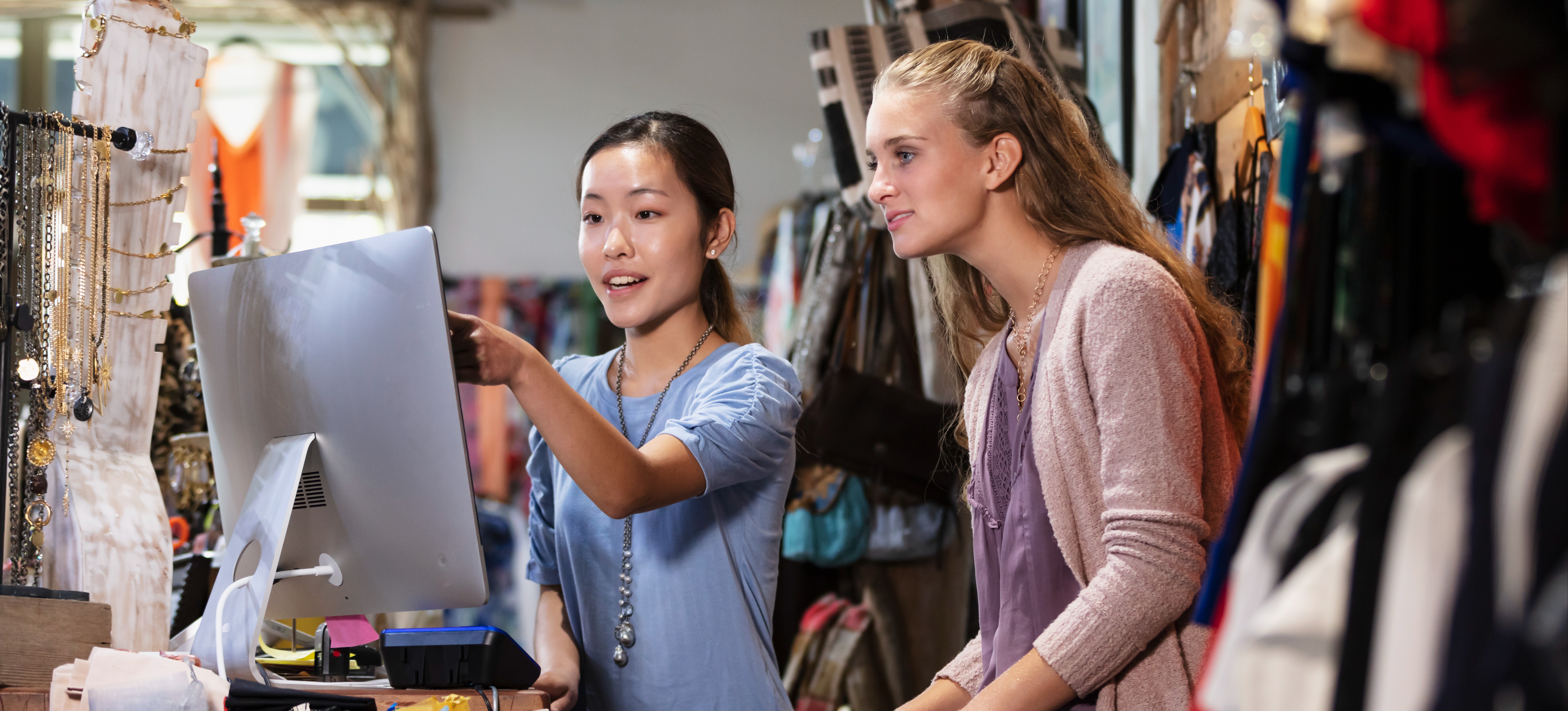 [Featured Image] Two coworkers discuss sales at their part-time jobs in a retail store.