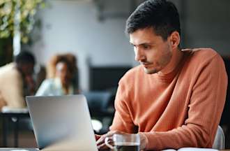 A student is seen typing on his laptop while sitting at his college library.